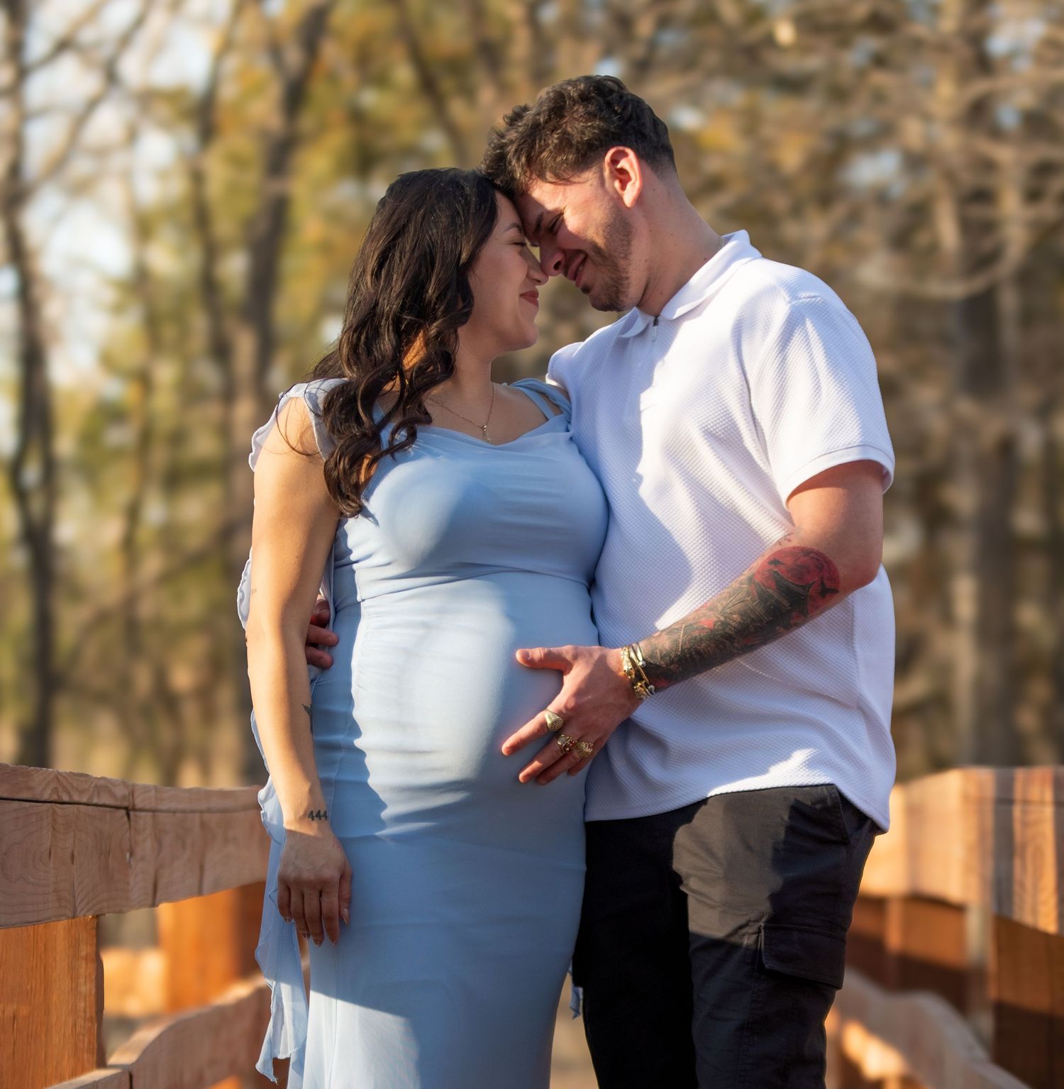 True-to-color maternity portrait of a couple on a wooden bridge at Hall County Park in Grand Island, NE.