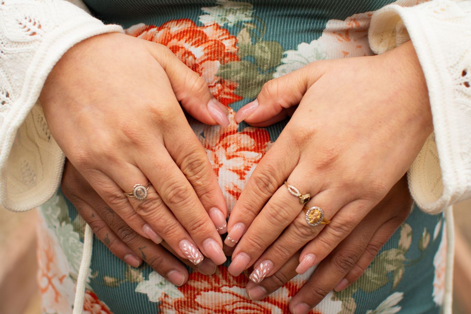 True-to-color close-up of a couple's hands resting on a maternity bump in Grand Island, Nebraska.