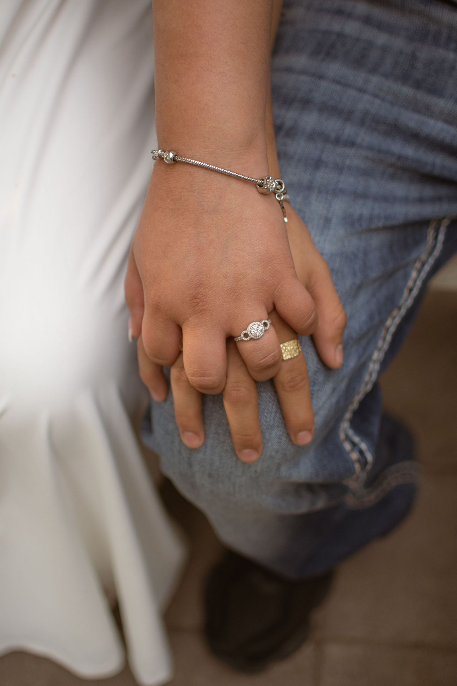 Intimate, clean close-up shot of a couple holding hands, highlighting a silver engagement ring, Grand Island, Nebraska.