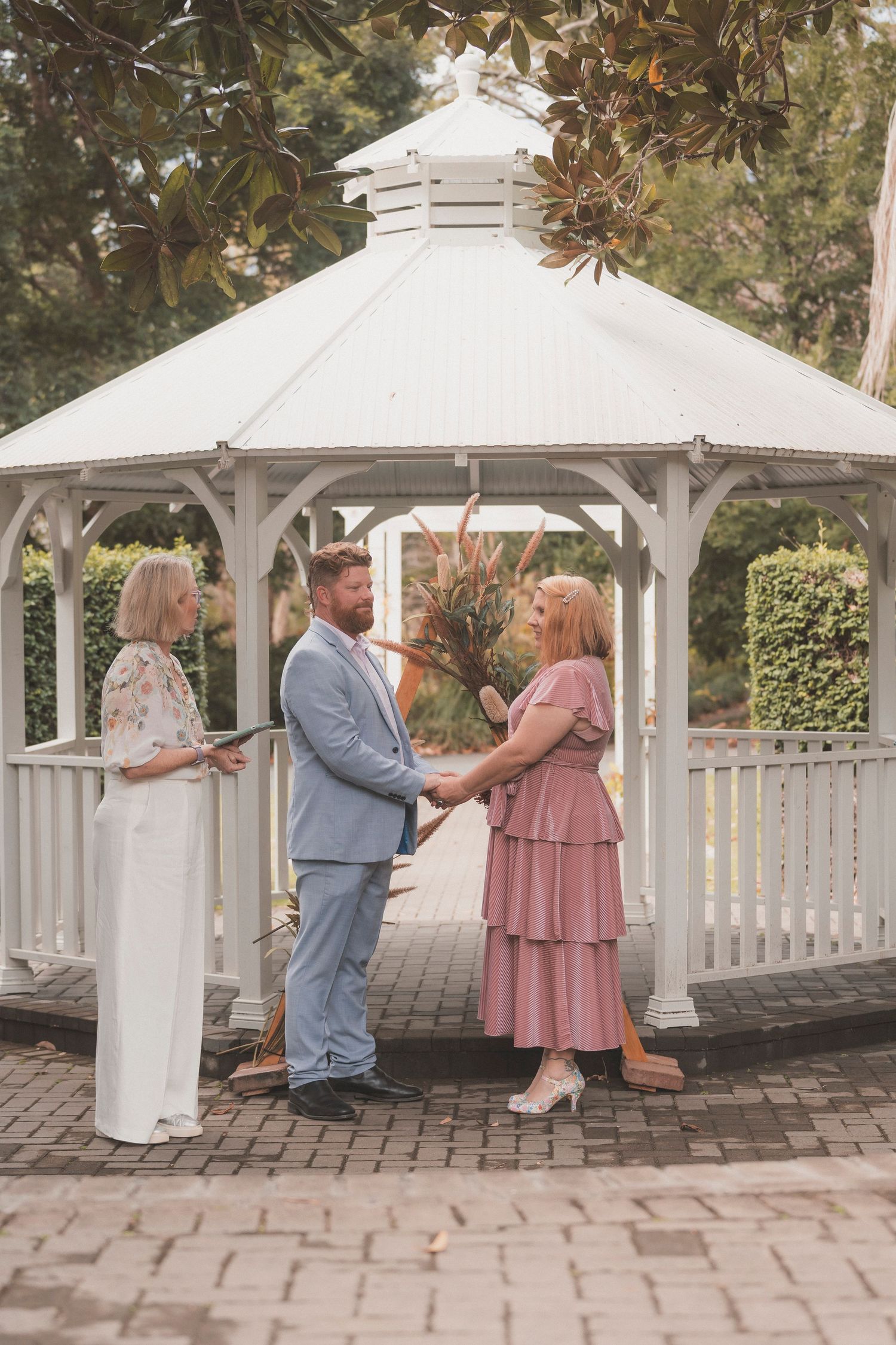 Bride and groom, elopement ceremony, Noosa botanic Gardens, standing with celebrant near pergola, photographed by Shae Imagery elopement