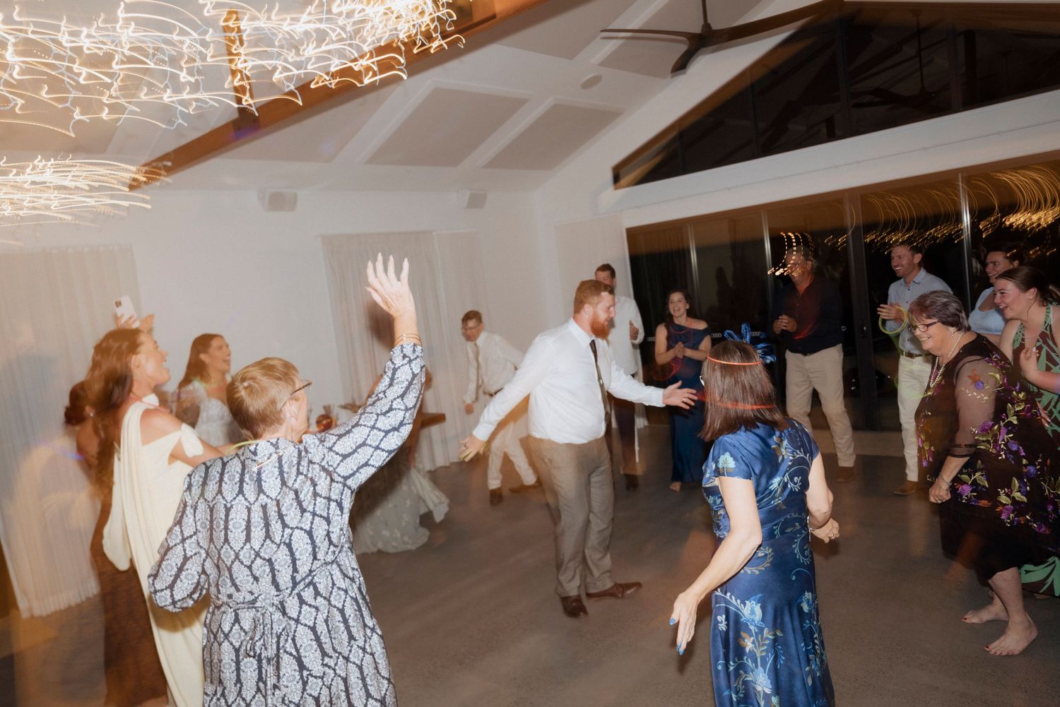 Newlyweds surrounded by family and friends on the dance floor.