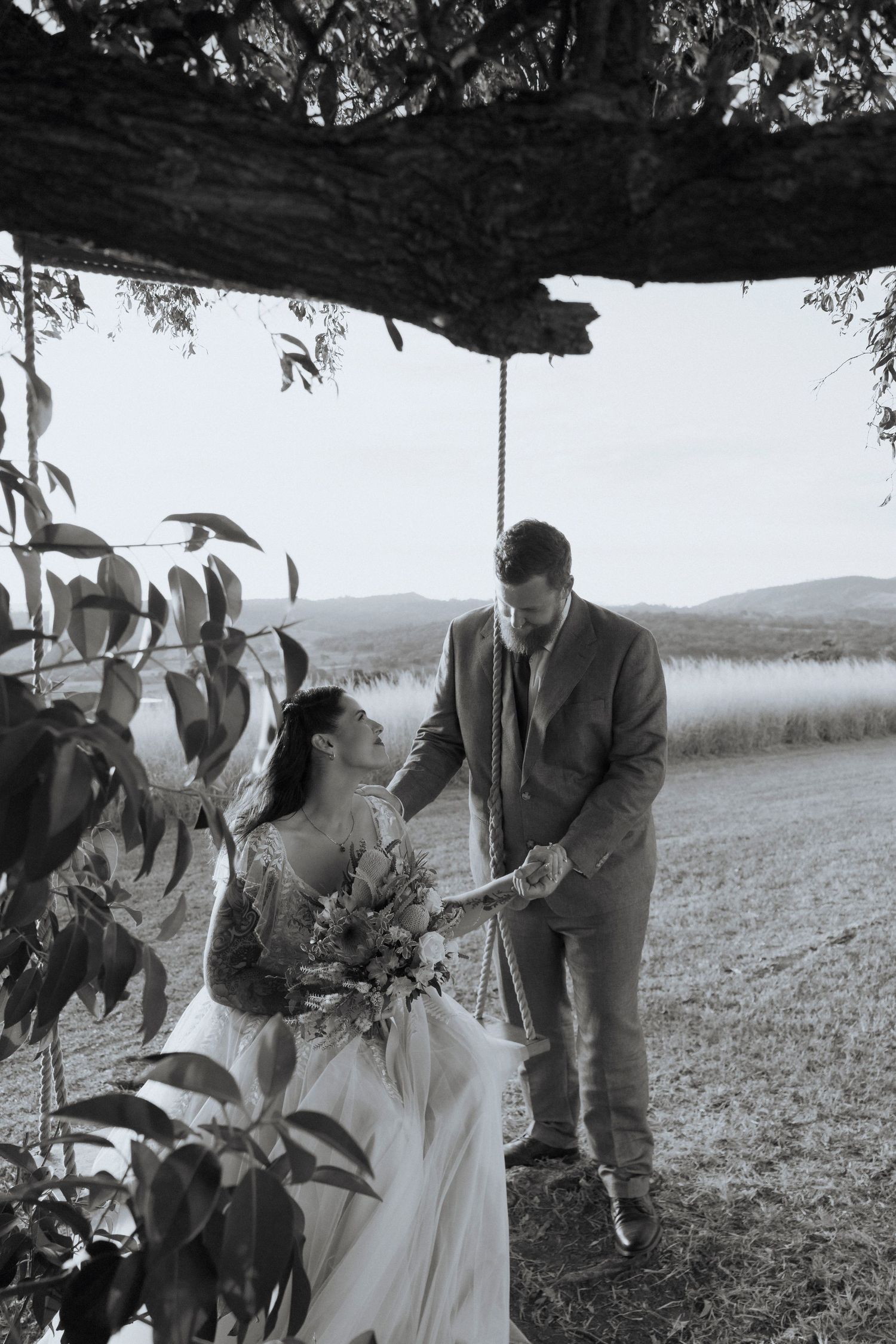 Newlyweds sharing a quiet moment beneath the tree with the swing overlooking the Scenic Rim valley.