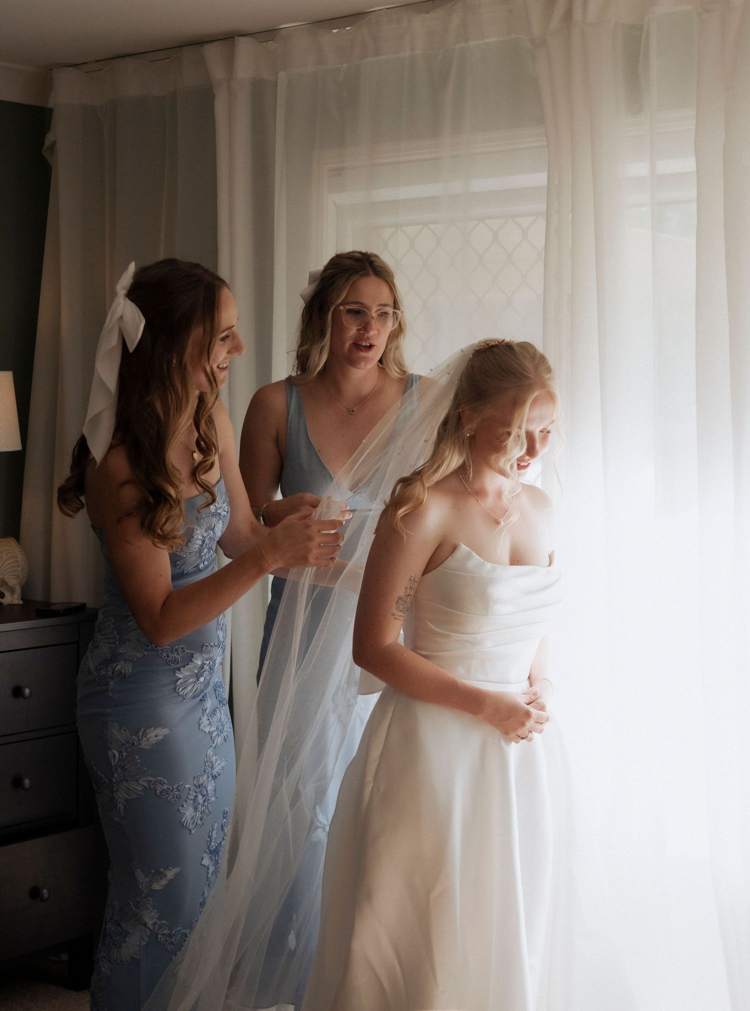 Wedding day getting ready, bide and bridesmaids indoors adjusting veil captured by Ipswihc wedding photographer Shae imagery