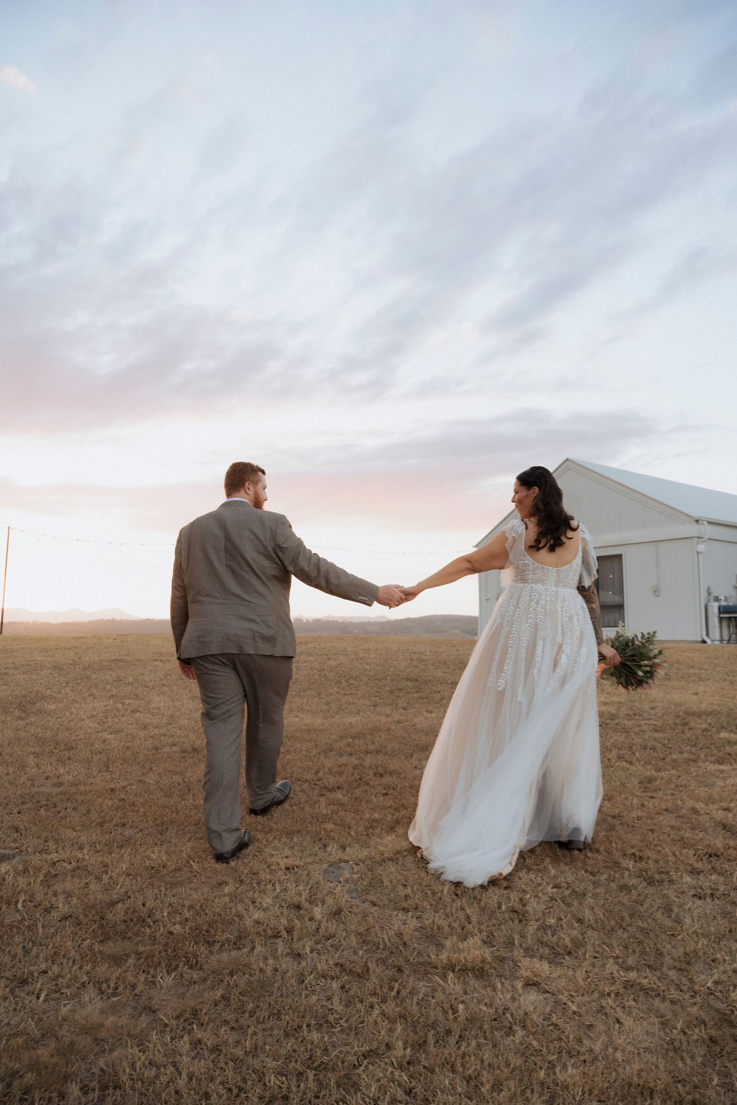 Bride and groom walking hand in hand through the grounds of Maroon Hill Estate.