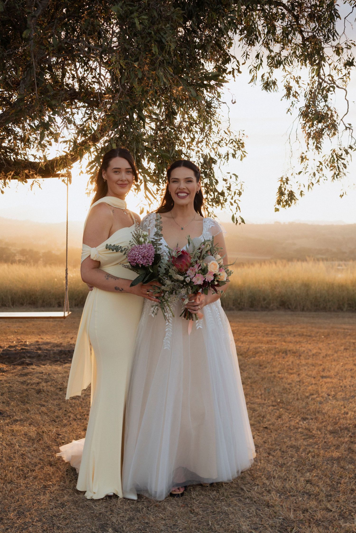 Bride standing beside the swing beneath the tree at Maroon Hill Estate during sunset.