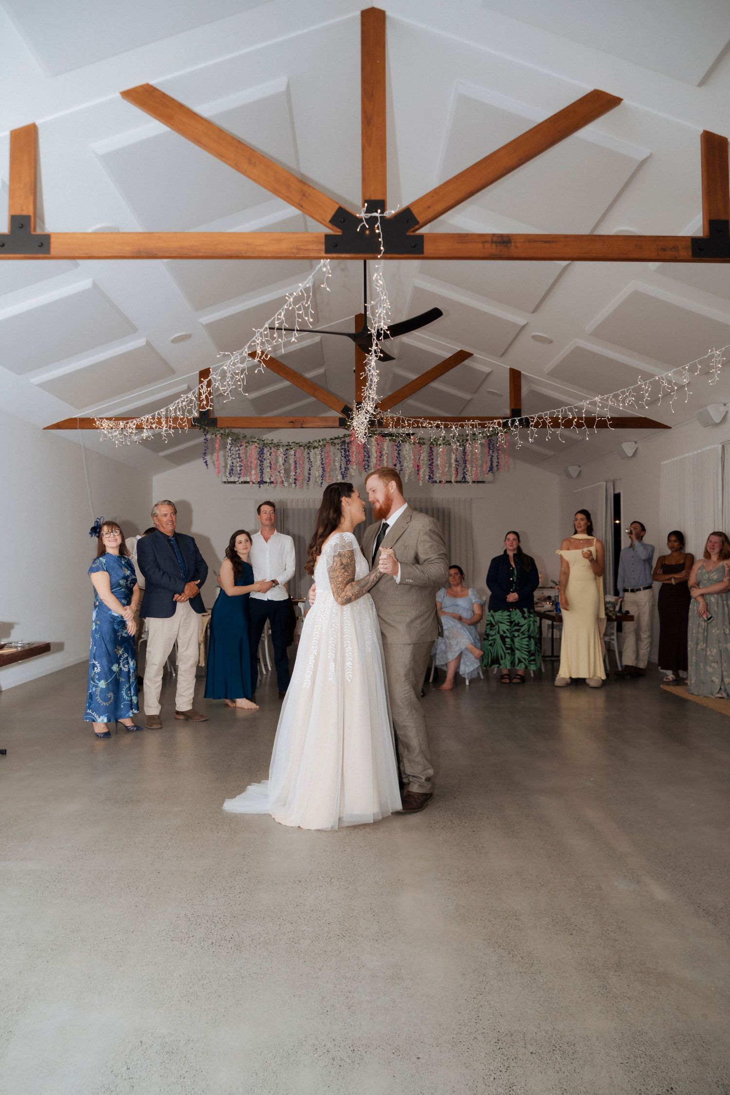 Bride and groom sharing their first dance beneath fairy lights at Maroon Hill Estate.