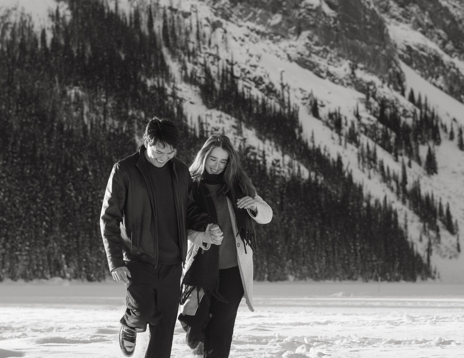 Couple walking through snow with mountain behind them