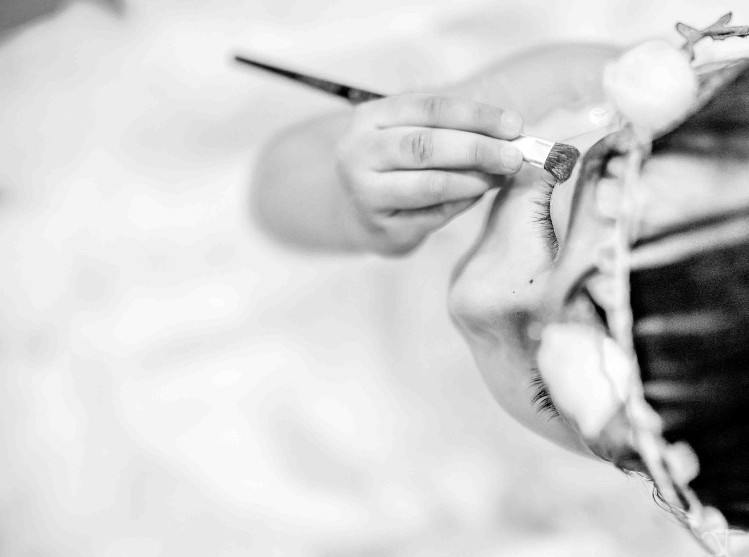 Close-up black and white image of a child's hand holding a delicate floral accessory.