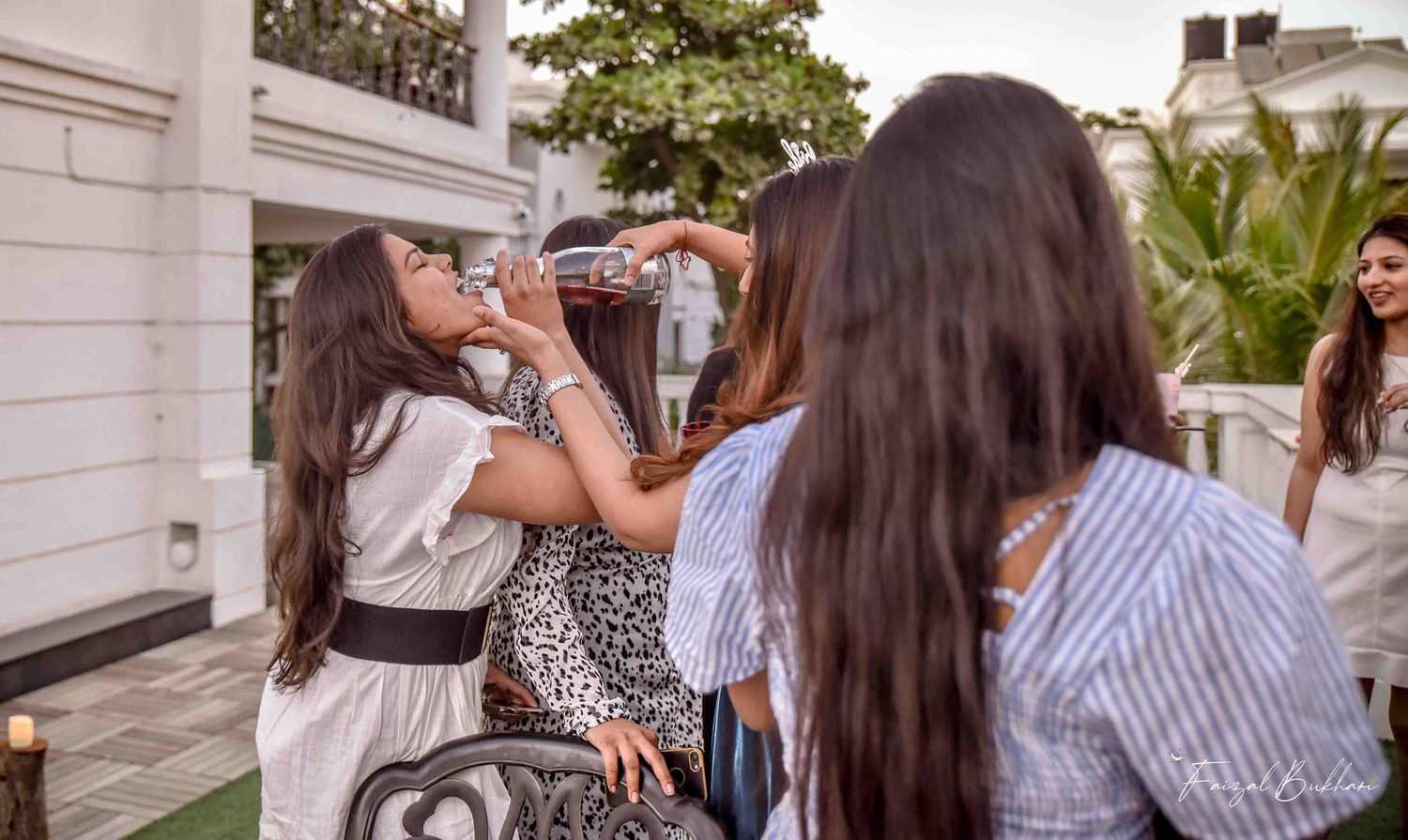 Women celebrating at outdoor bridal shower party with one guest drinking from a bottle.