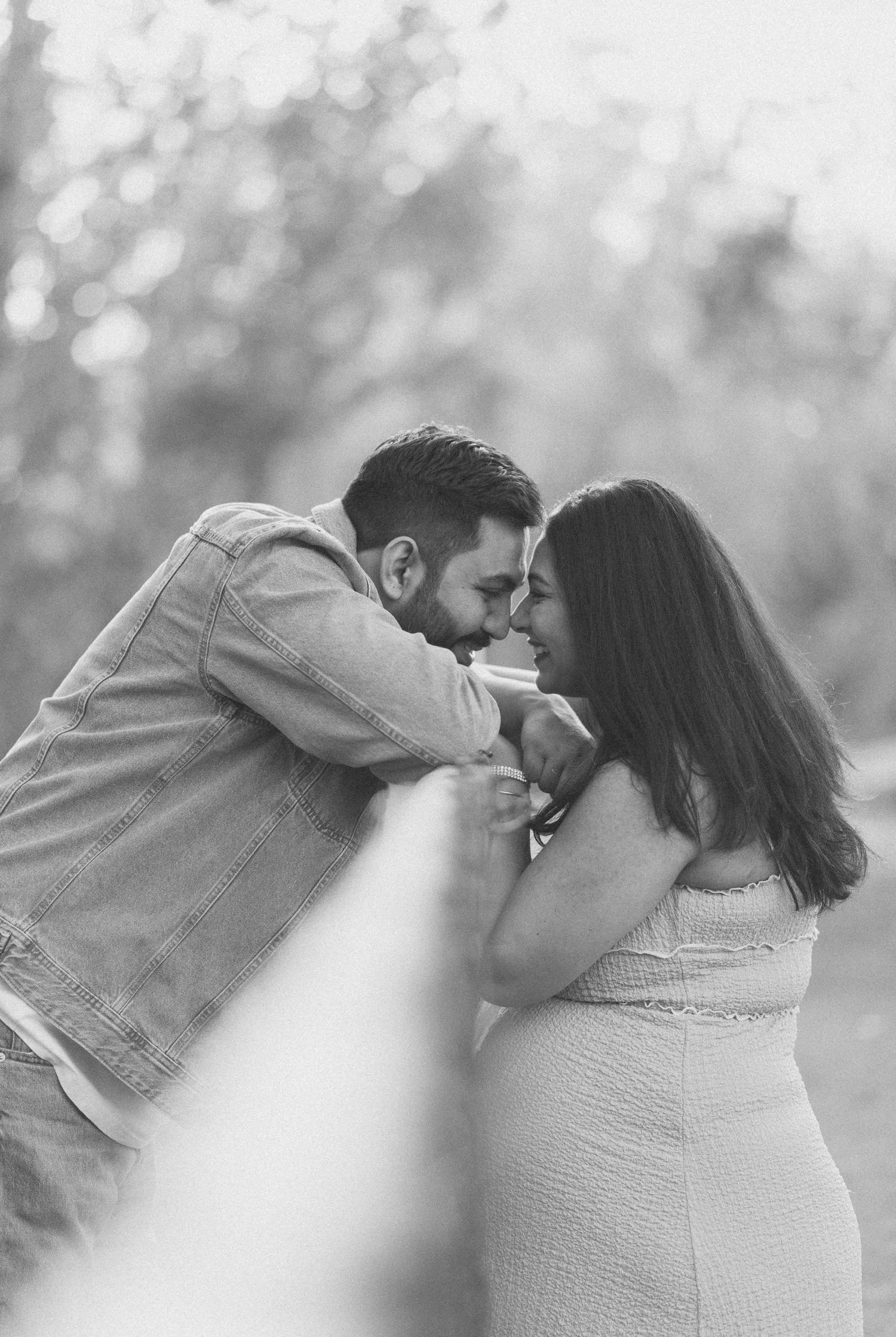 Couple sharing intimate forehead touch moment in black and white maternity portrait.