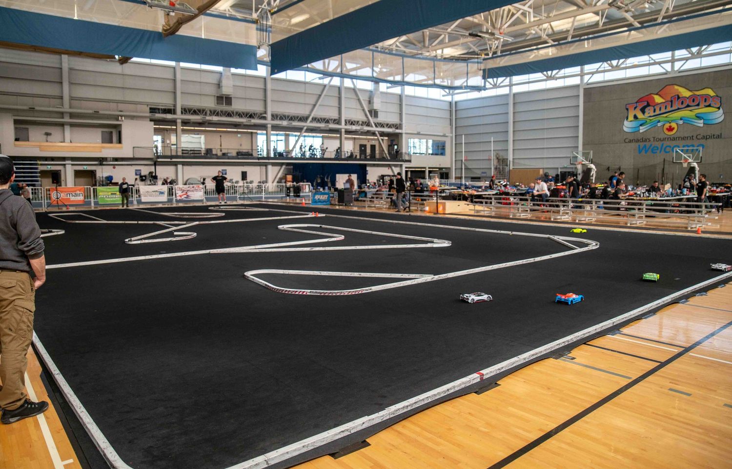 Wide-angle view of a large indoor RC car racing track set up in a gymnasium.