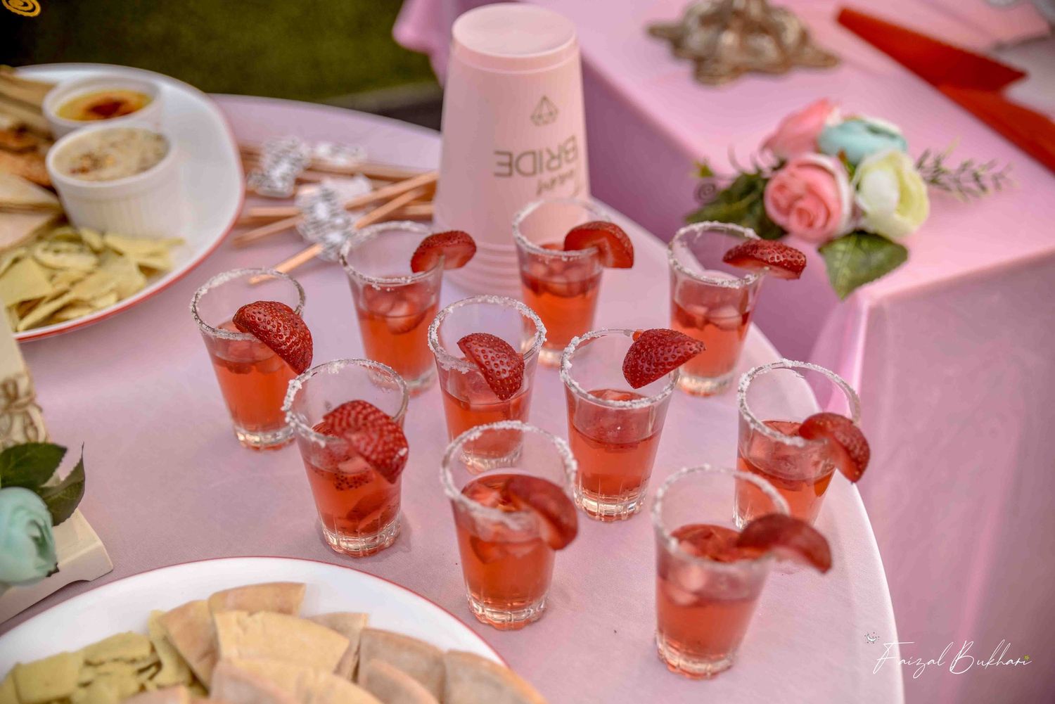 Pink strawberry cocktail shots with Team Bride cup at elegant outdoor bridal shower.