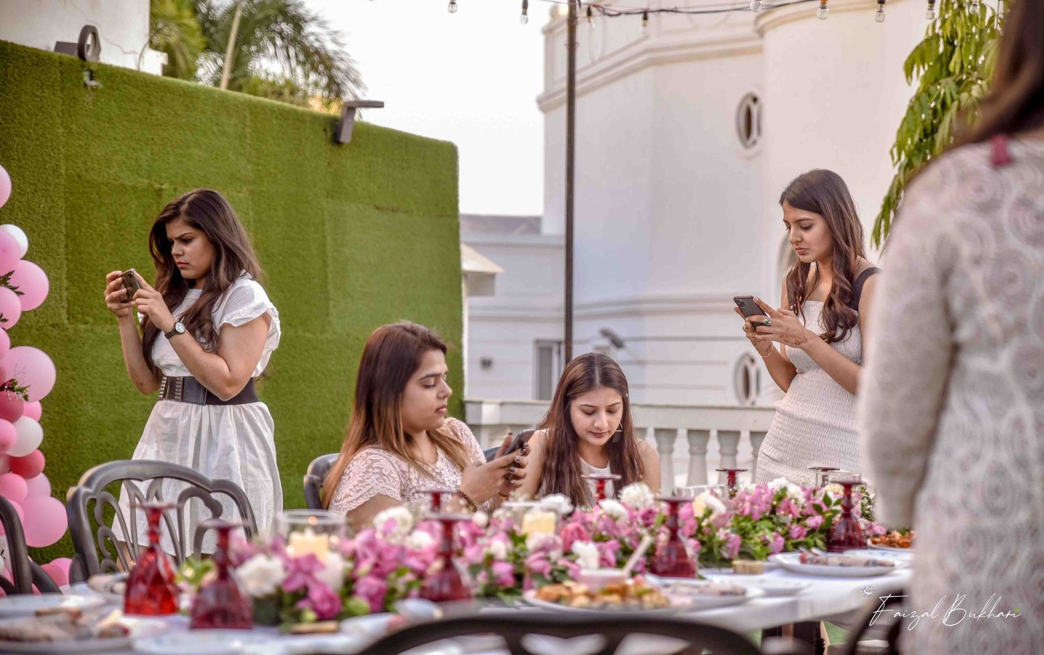 Girls using phones at a beautifully decorated outdoor bridal shower party.