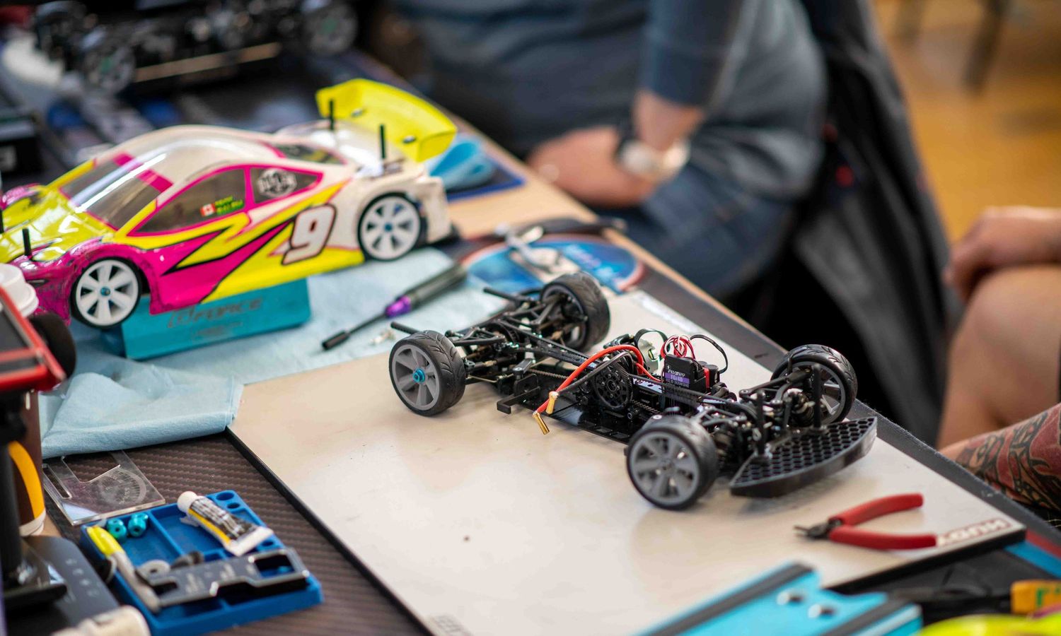 RC car chassis being assembled on workbench at hobby racing competition.