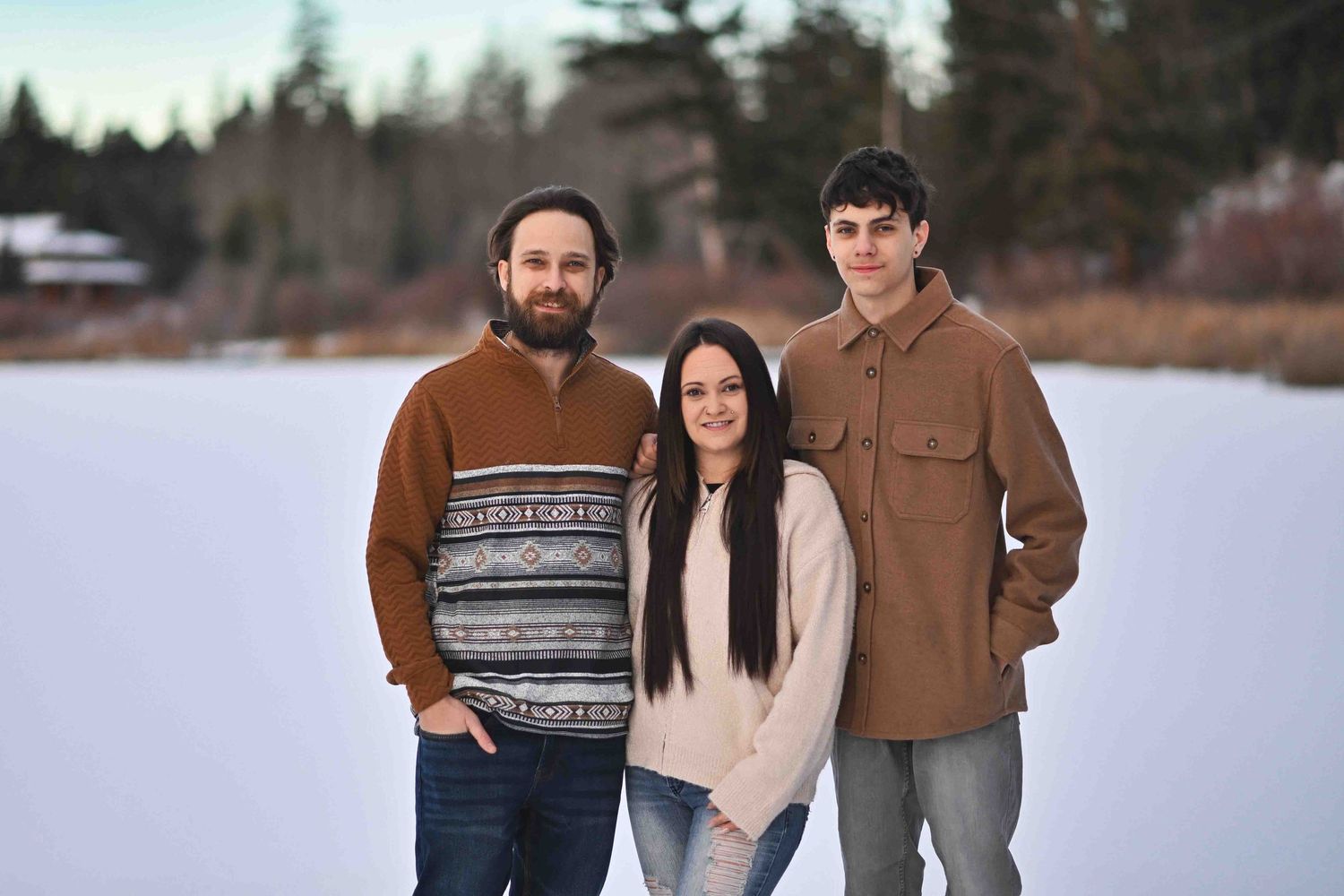 Three friends posing together for a portrait on a snowy frozen lake during a winter outdoor photoshoot.