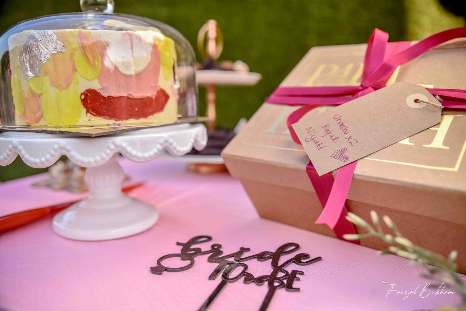 Close-up of colorful bridal shower cake under glass dome with Bride to Be cake topper.