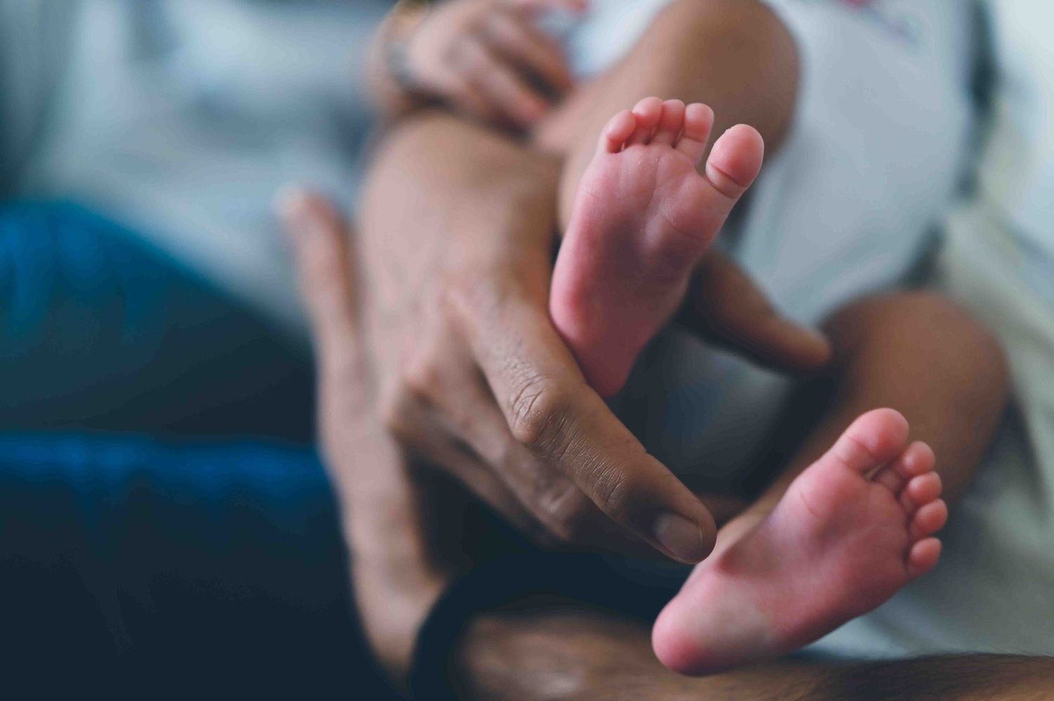 Close-up of parents gently holding their newborn baby's tiny feet.