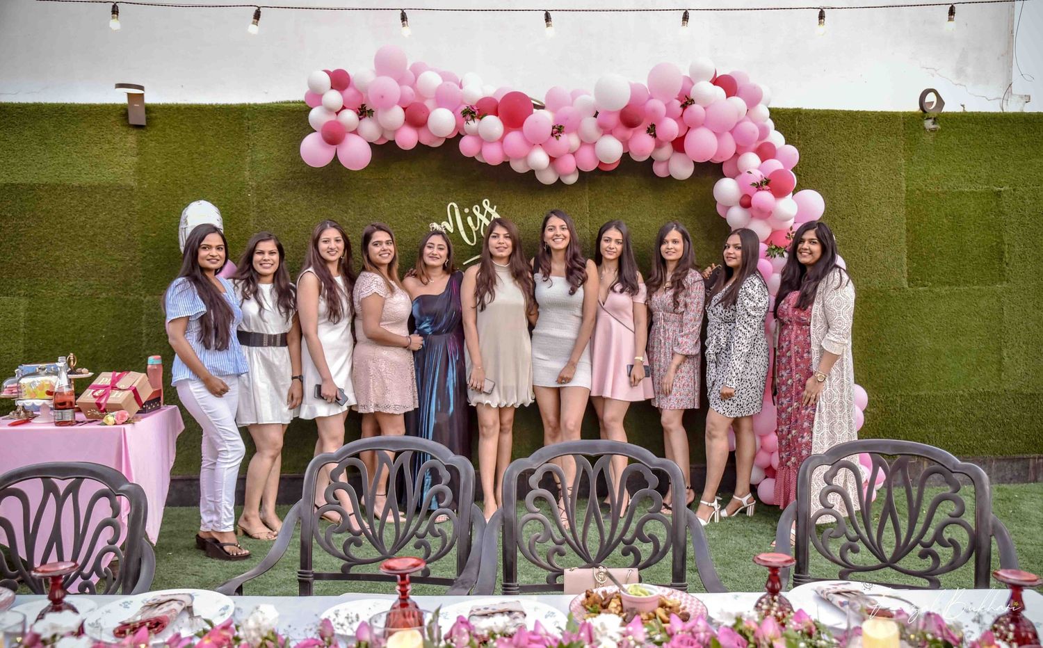 Group of women posing under pink balloon arch at a Miss to Mrs bridal shower party.