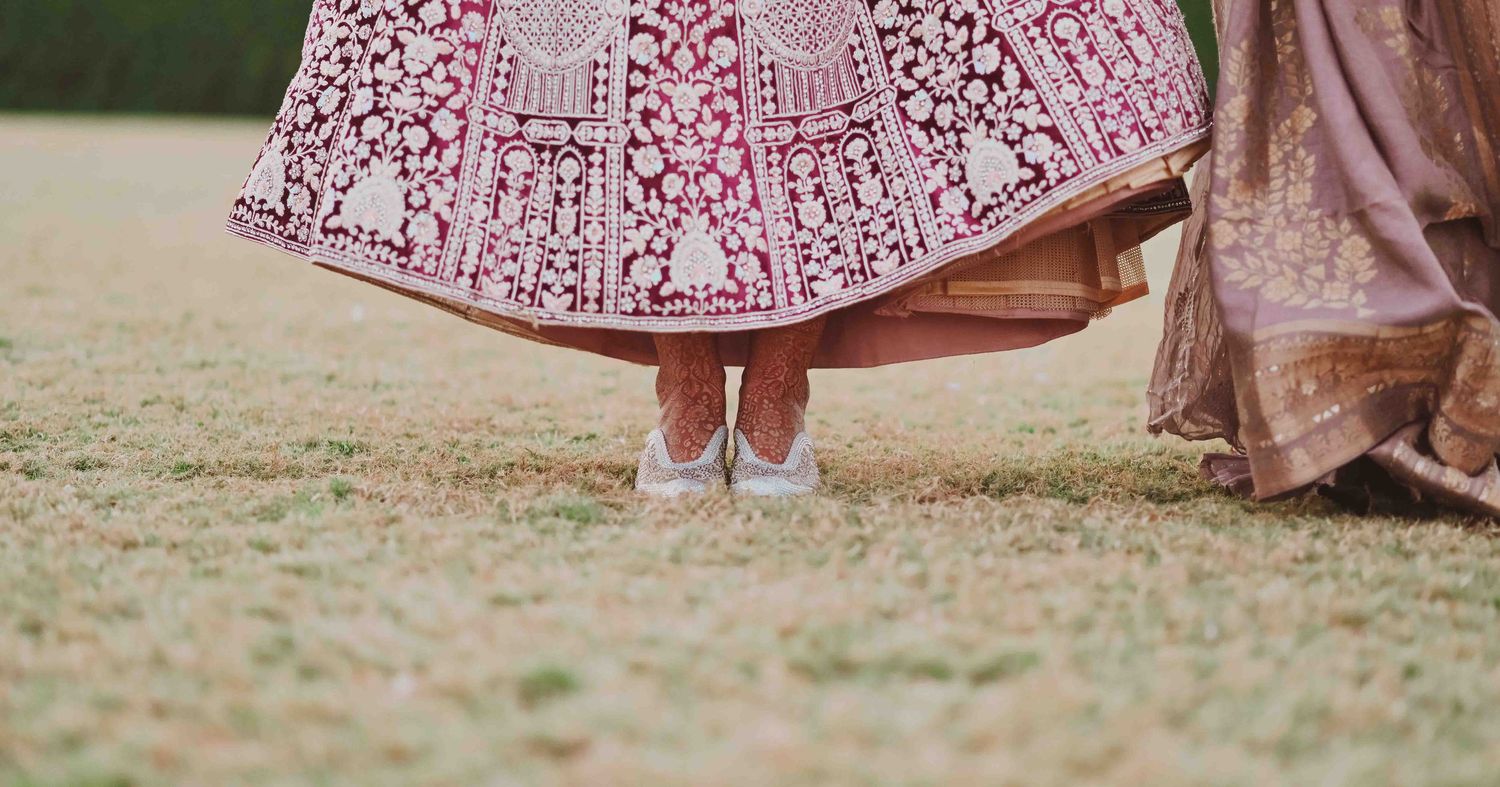 Indian bride twirling pink embroidered lehenga, silver juttis visible beneath the skirt.