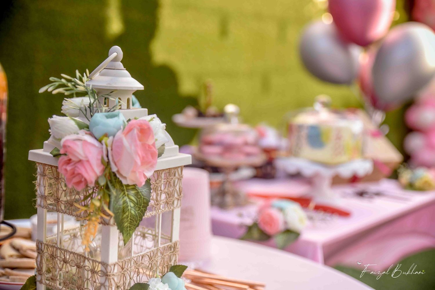 Elegant pink bridal shower dessert table with white lantern centerpiece, flowers, and balloons.
