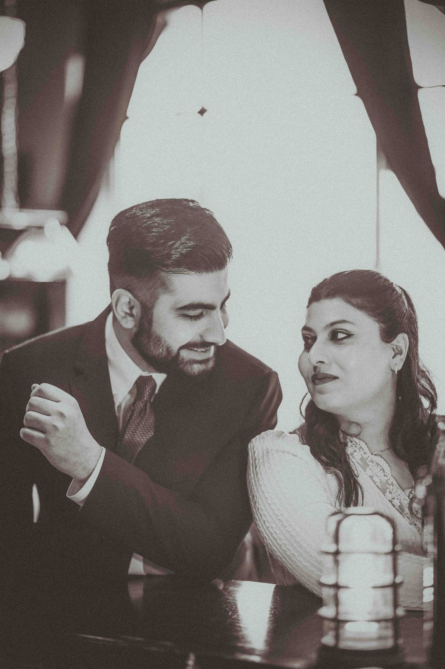 Couple sharing an intimate moment at a table, black and white wedding photo.