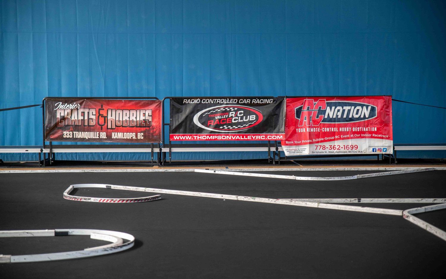 RC car racing track with sponsor banners including RC Nation against blue wall.
