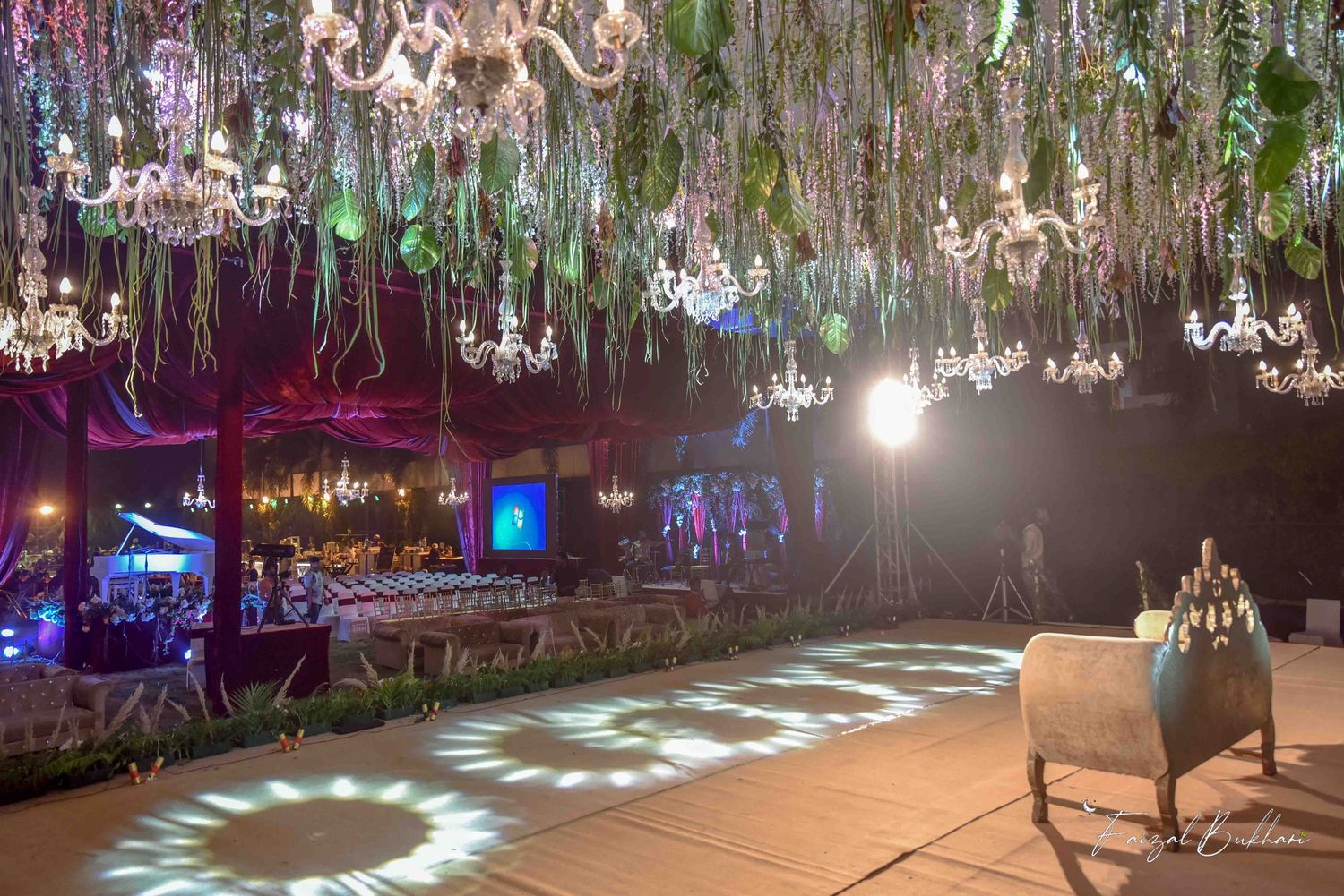 Enchanting outdoor wedding reception with crystal chandeliers suspended above a glowing dance floor.
