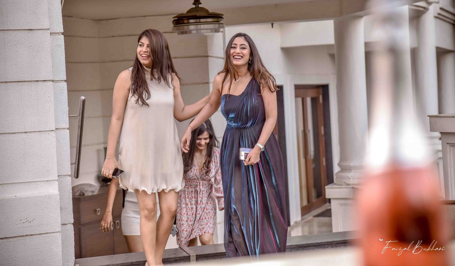 Three women and a child walking on a porch at an outdoor celebration event.