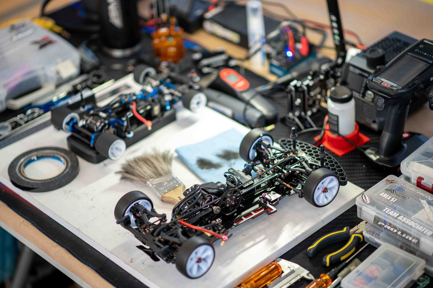 Detailed RC car chassis with electronics on a workbench during an RC racing competition.