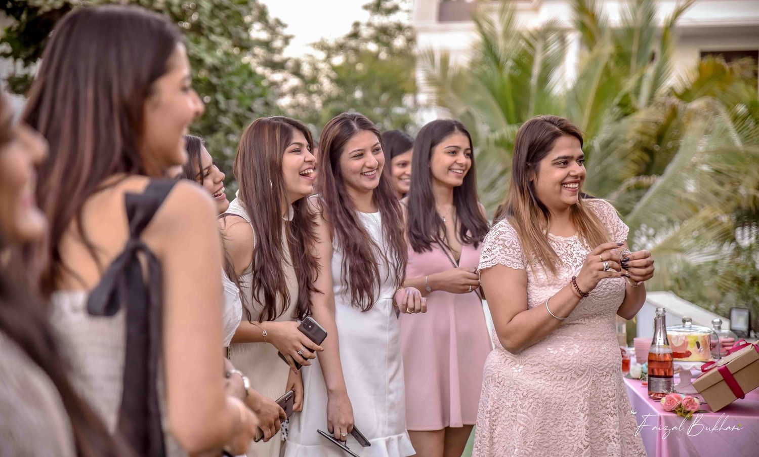 Group of elegantly dressed women laughing and socializing at an outdoor bridal shower.