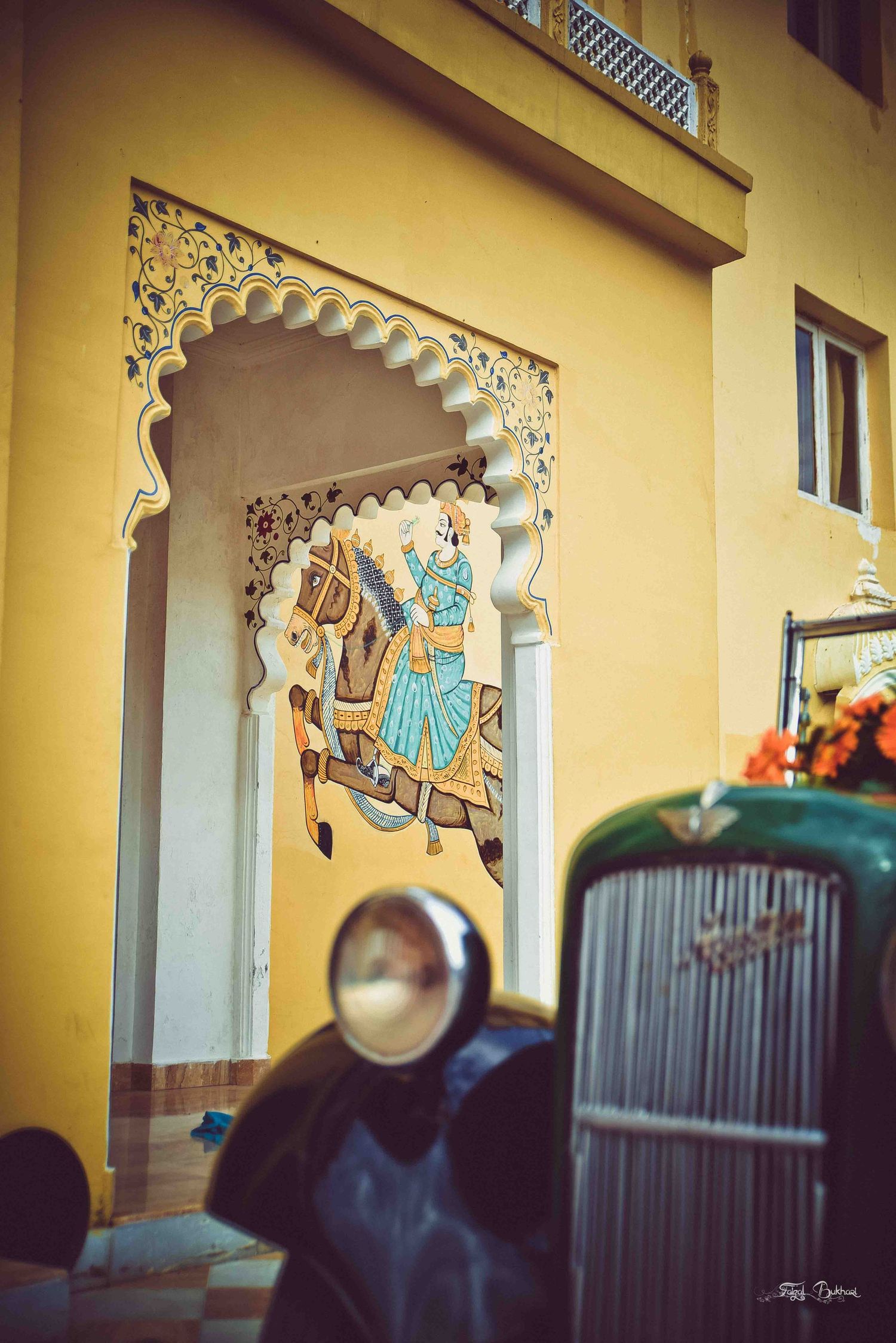 Traditional Indian mural painting of a royal figure on horseback adorning a yellow heritage building facade.