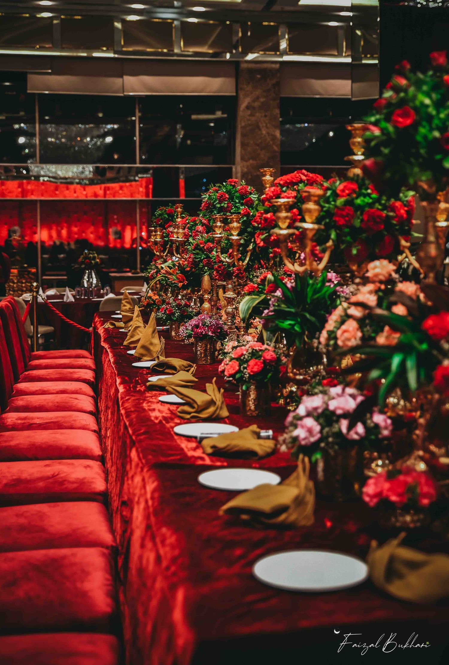 Stunning red velvet banquet table adorned with gold candelabras and lush floral arrangements at Indian wedding.