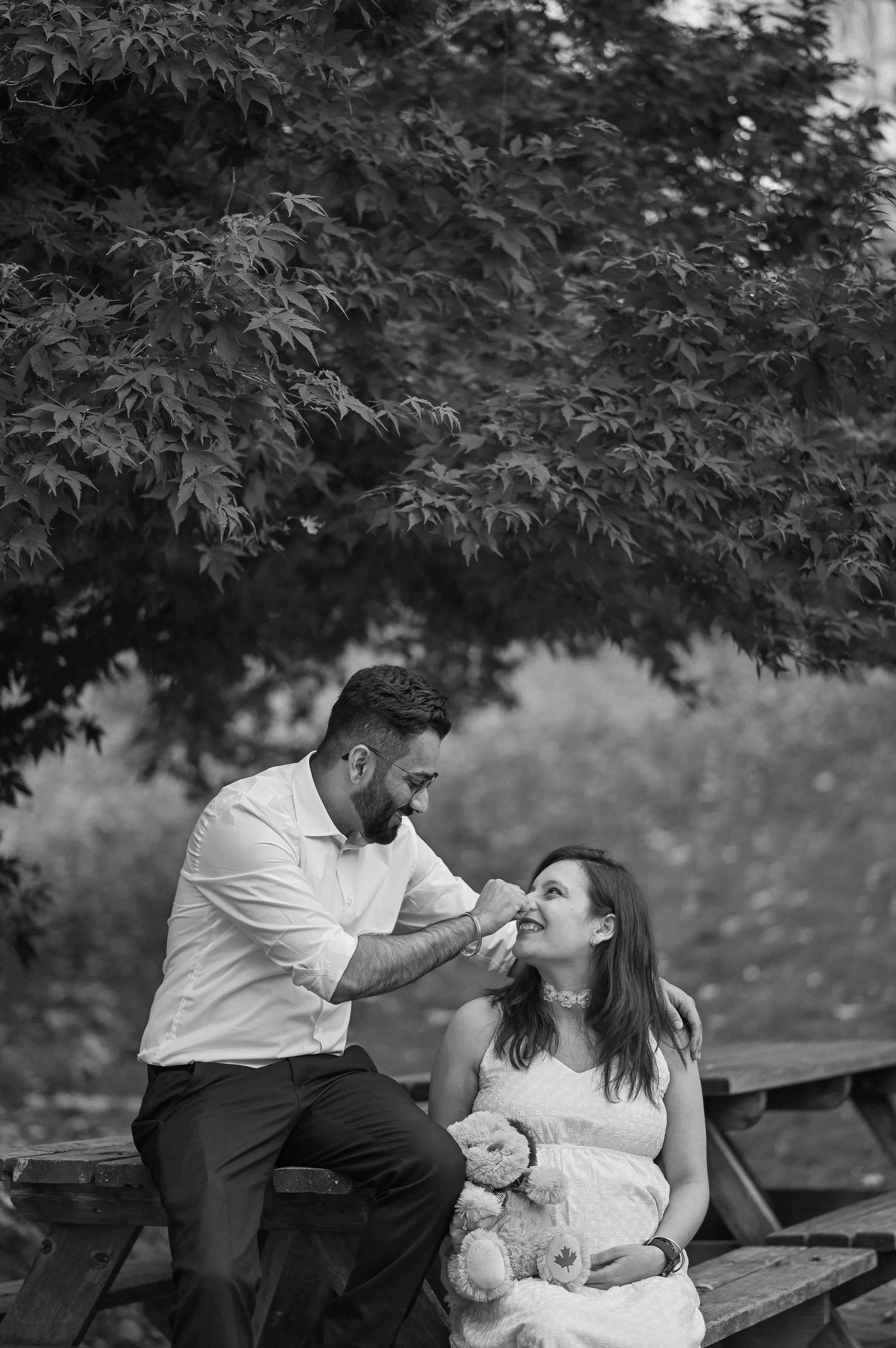Black and white photo of man tenderly feeding woman at a picnic table.