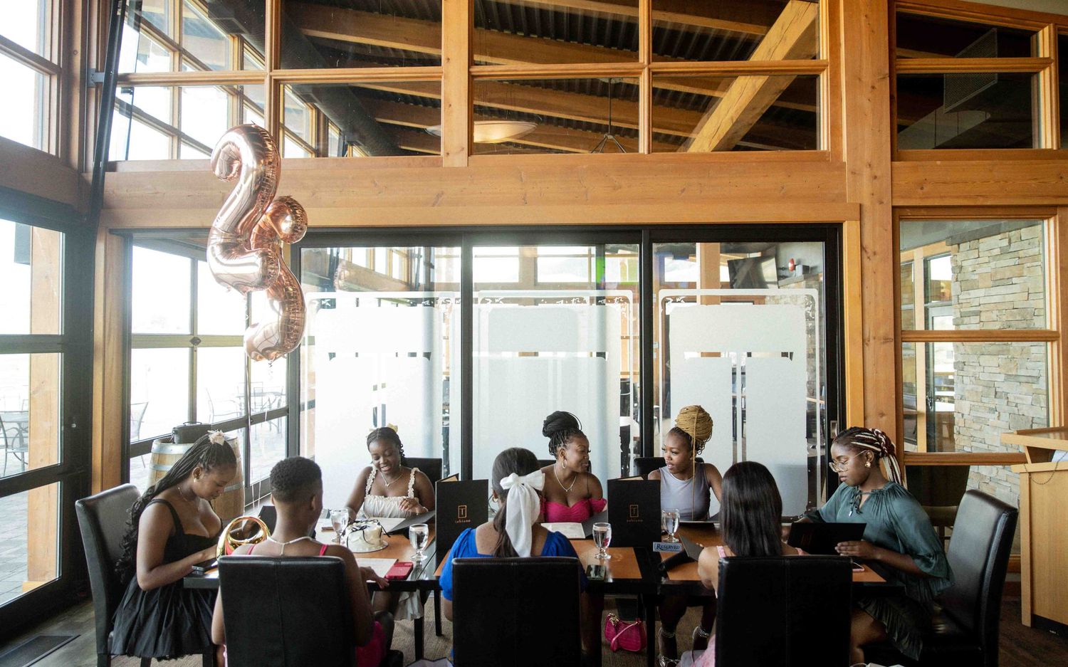 Group of women dining together at restaurant table decorated with rose gold number balloon.