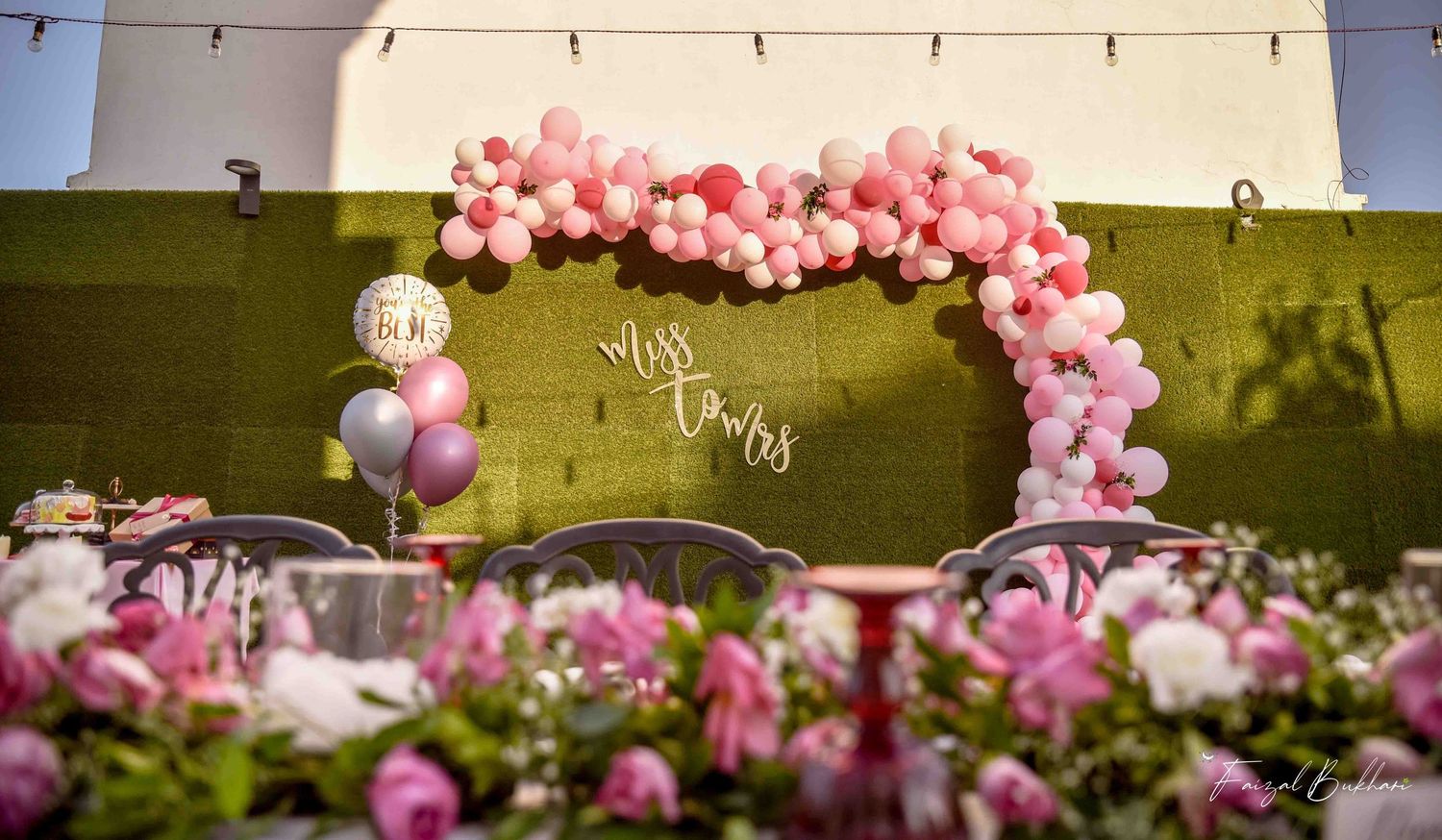 Pink and white balloon arch over Miss to Mrs sign at outdoor bridal shower party.