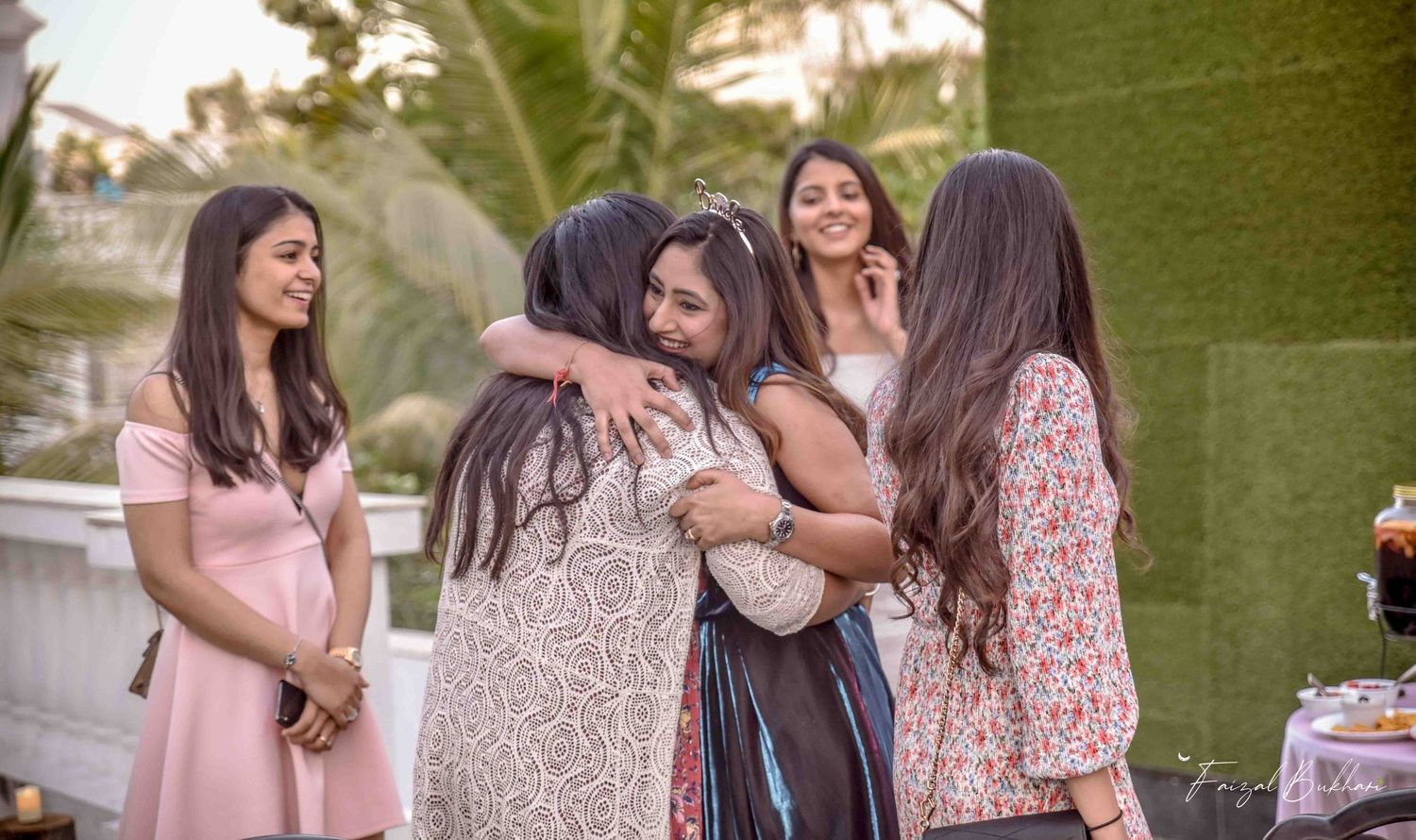 Group of women sharing warm hugs at an elegant outdoor party celebration.