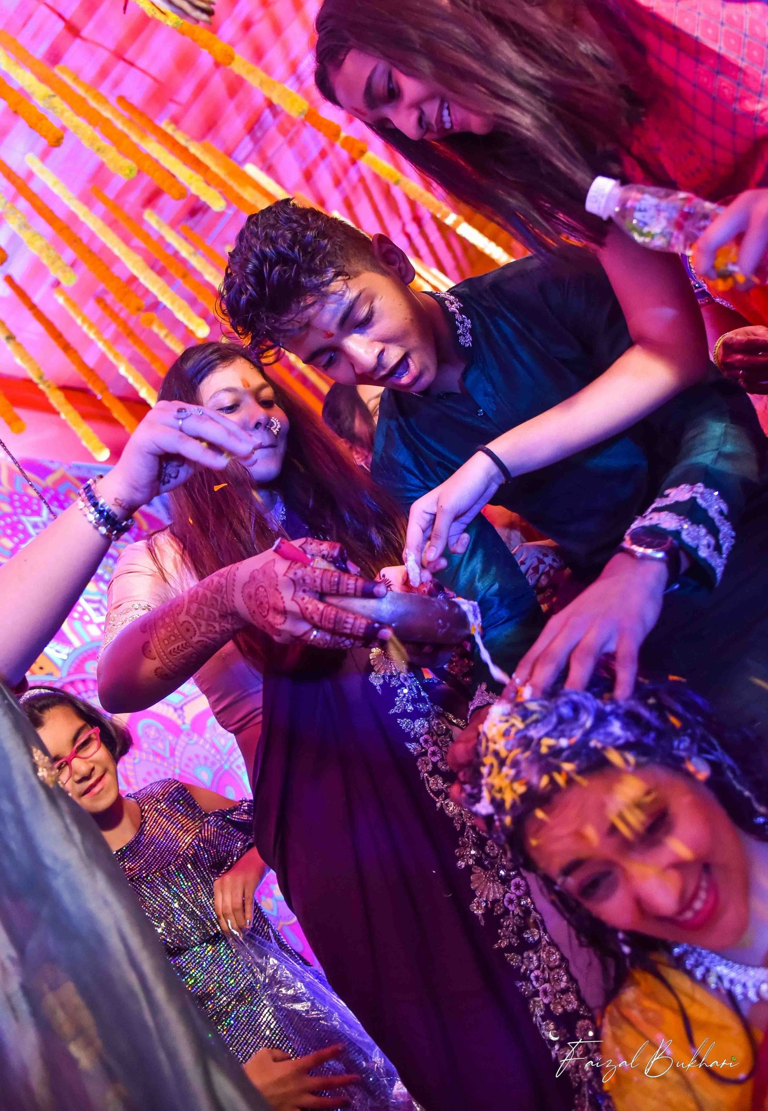 Guests applying haldi turmeric paste on bride during colorful Indian pre-wedding haldi ceremony.