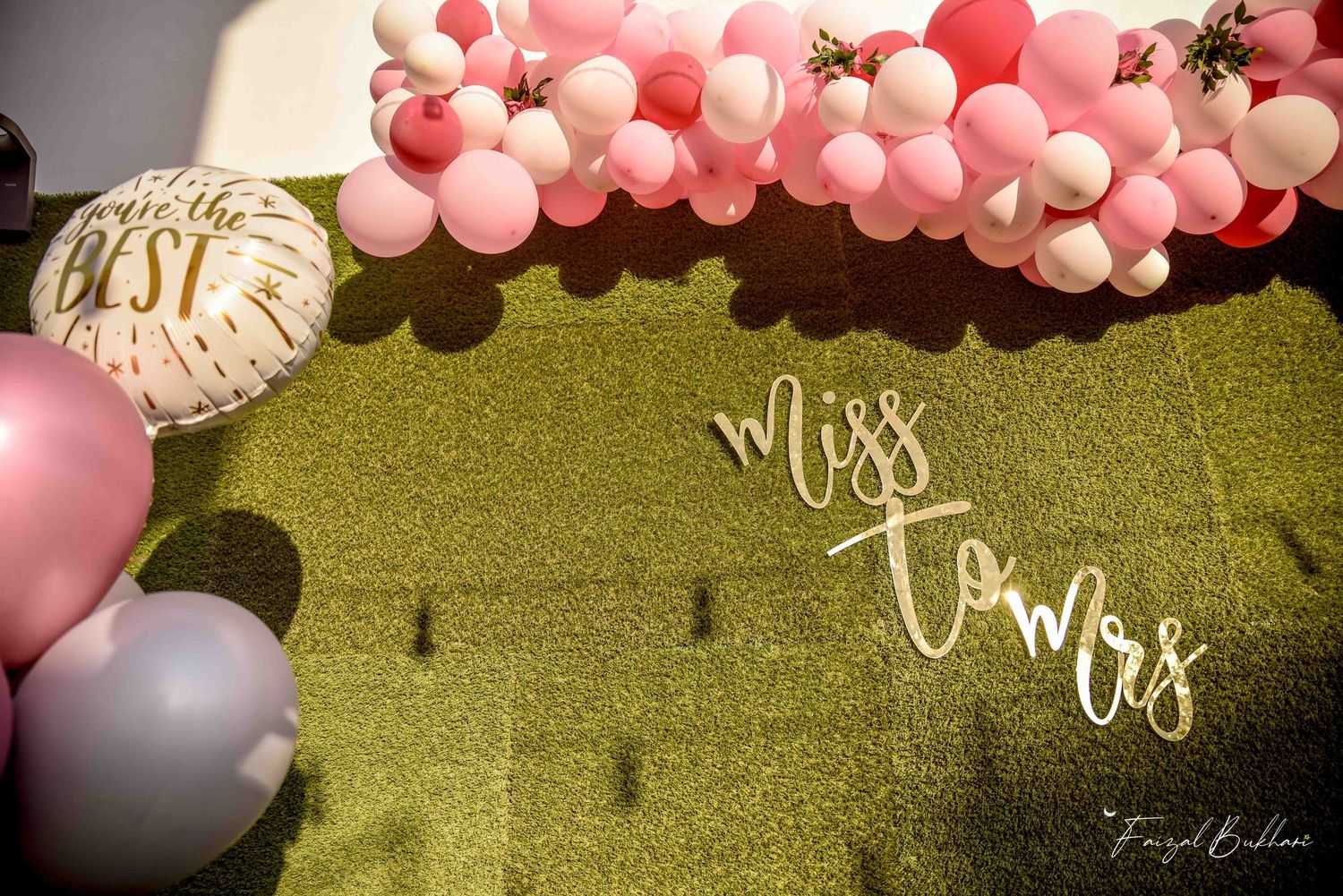 Miss to Mrs gold script sign on green wall with pink balloons.