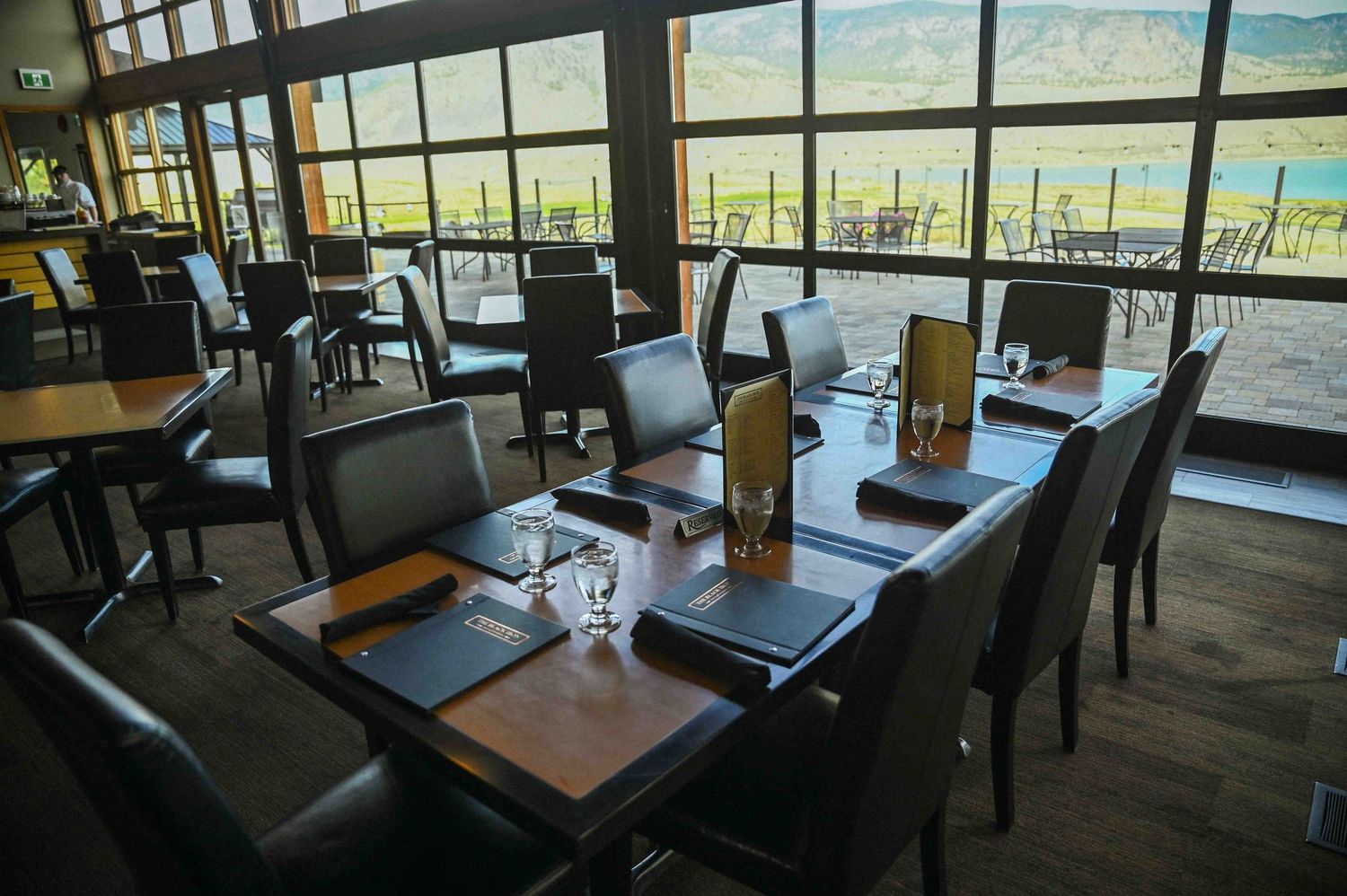 Elegant restaurant interior with leather chairs, wooden tables, and scenic mountain vineyard views.