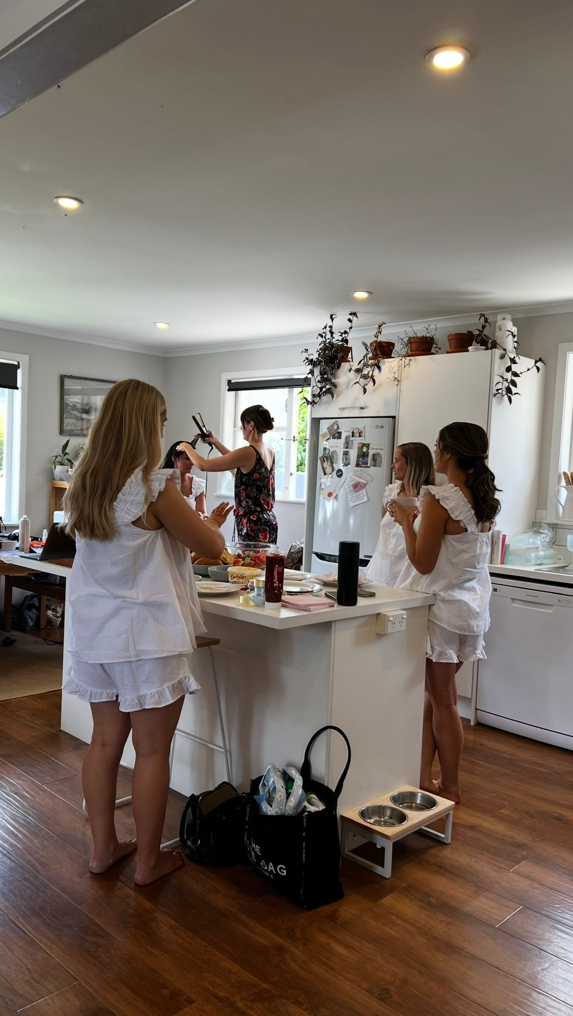 A group dressed in white outfits gathers around a kitchen counter during a cooking or crafting activity.