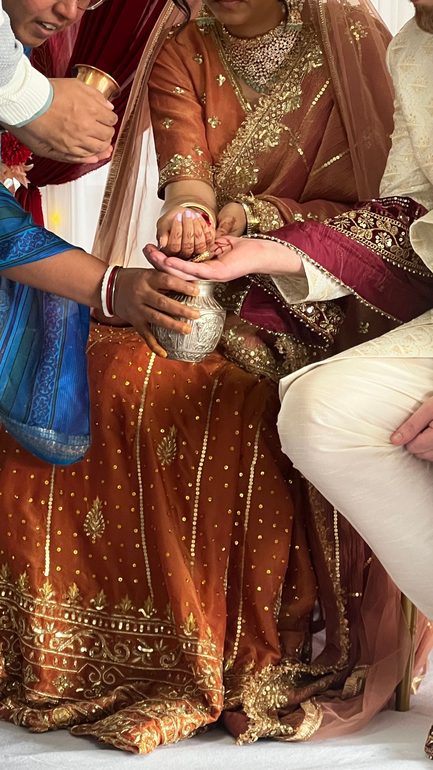 Close-up details of ornate brown and gold Indian wedding attire with intricate embroidery and beadwork.