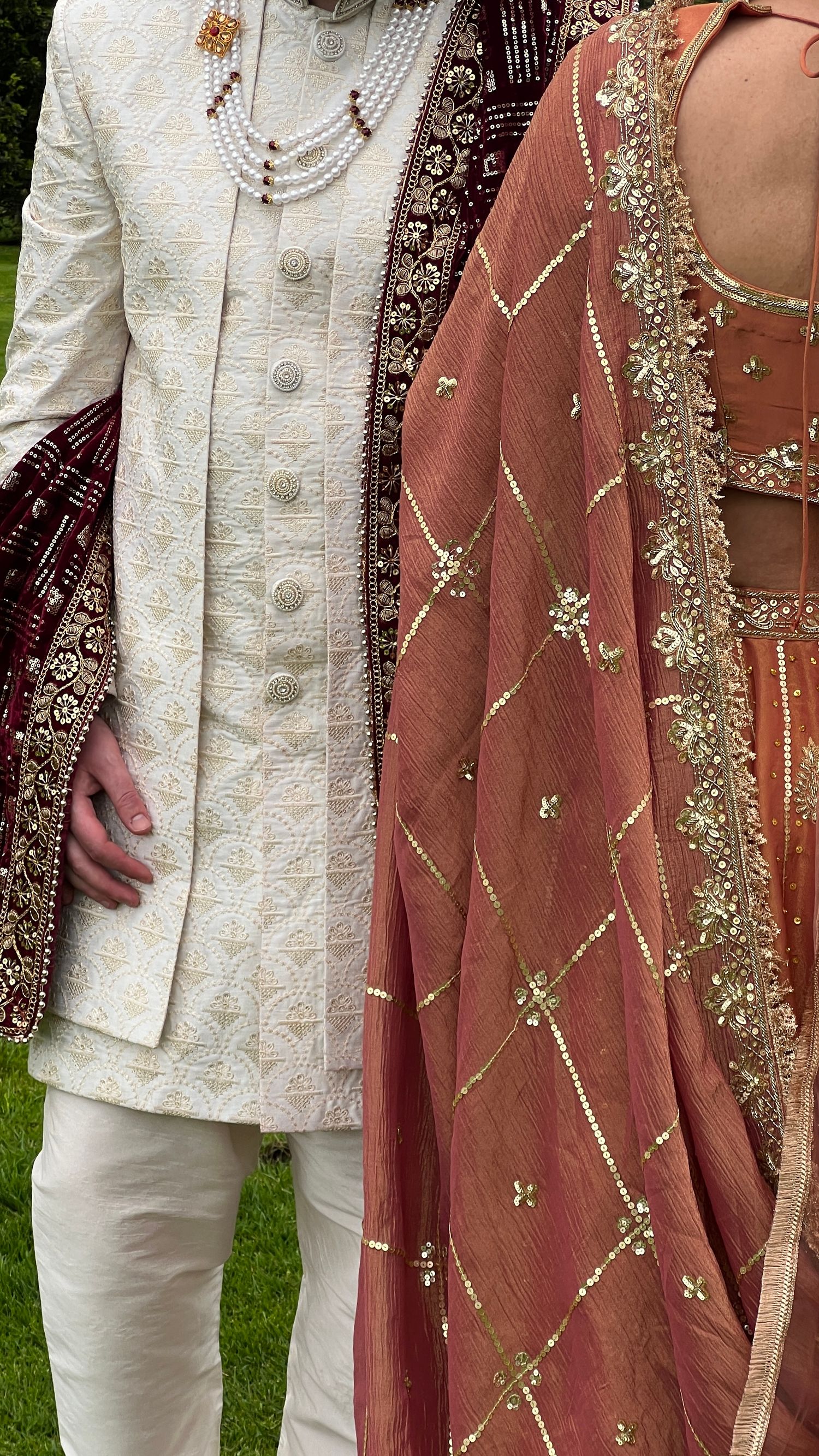 Elegant Indian wedding attire featuring white embroidered sherwani and rust-colored dupatta with gold detailing.