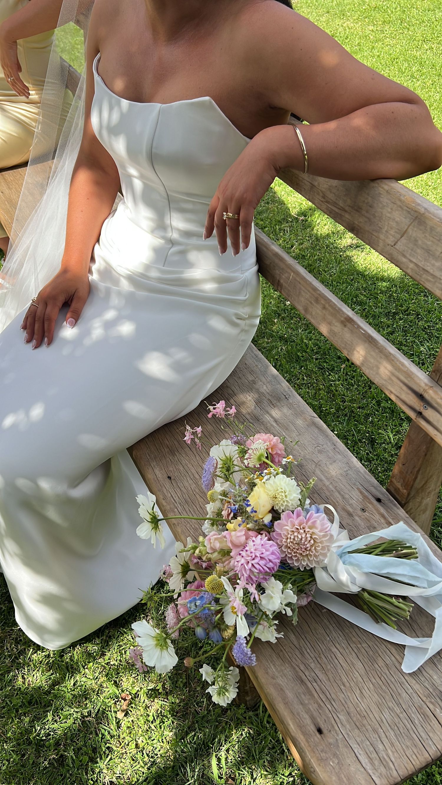 Wedding bouquet with pastel flowers resting on a wooden bench outdoors. content creation in new zealand