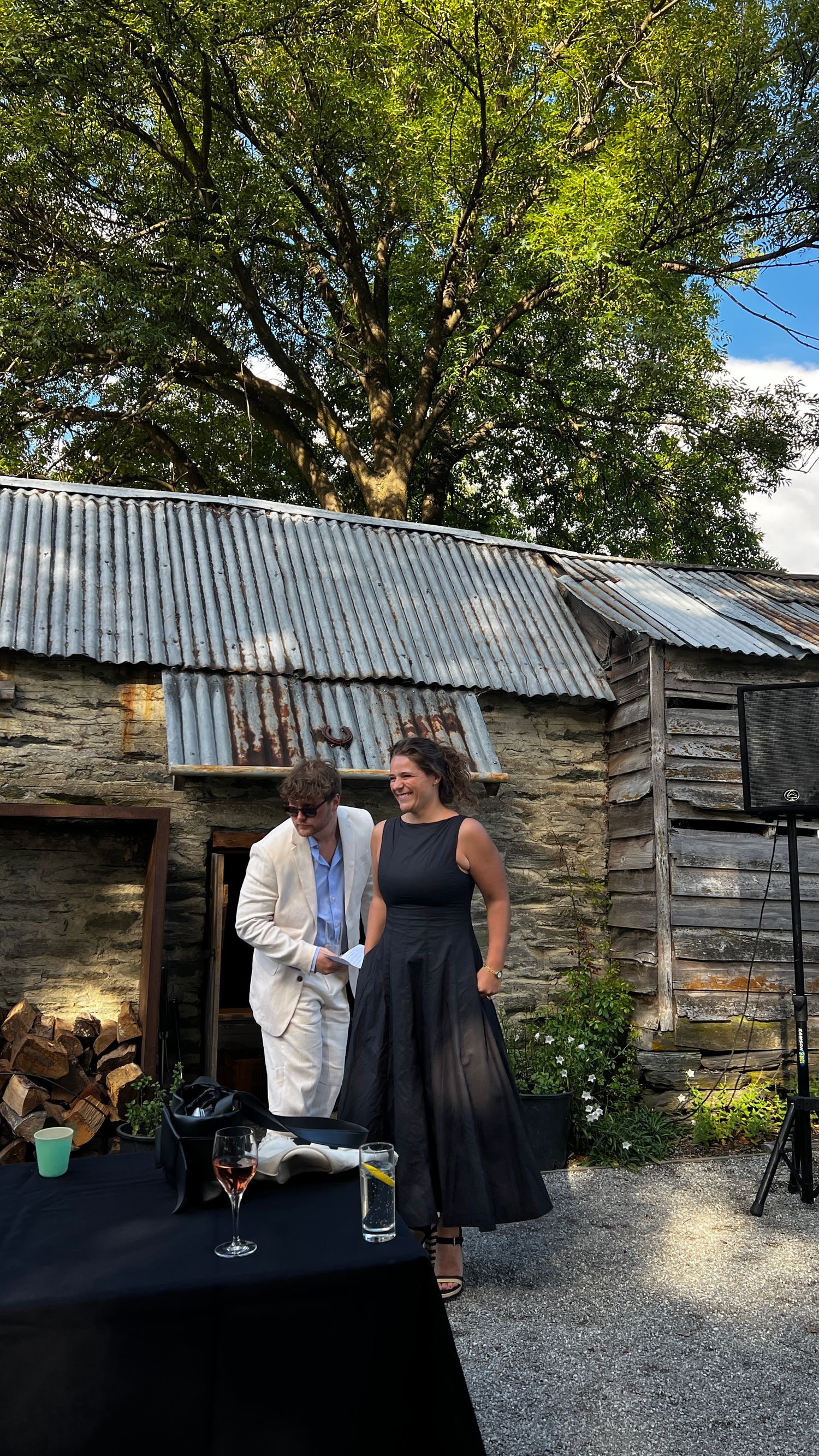 Outdoor gathering at a rustic venue with wooden structures and natural lighting.