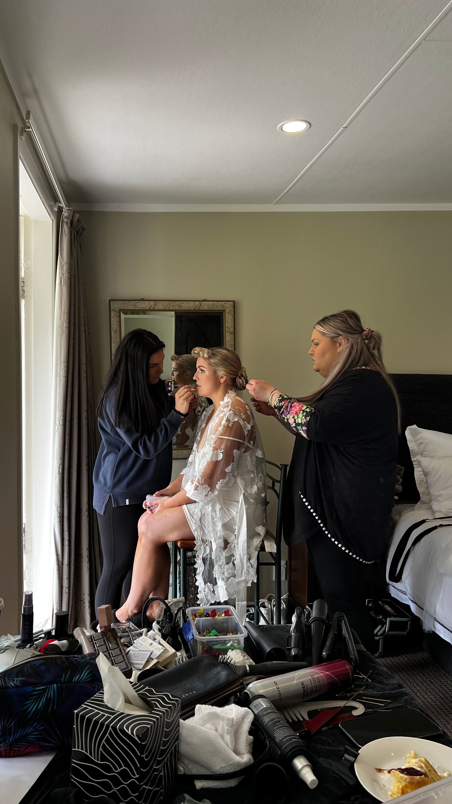 Wedding preparation scene with people getting ready in a bright room with makeup and styling. content creation in new zealand
