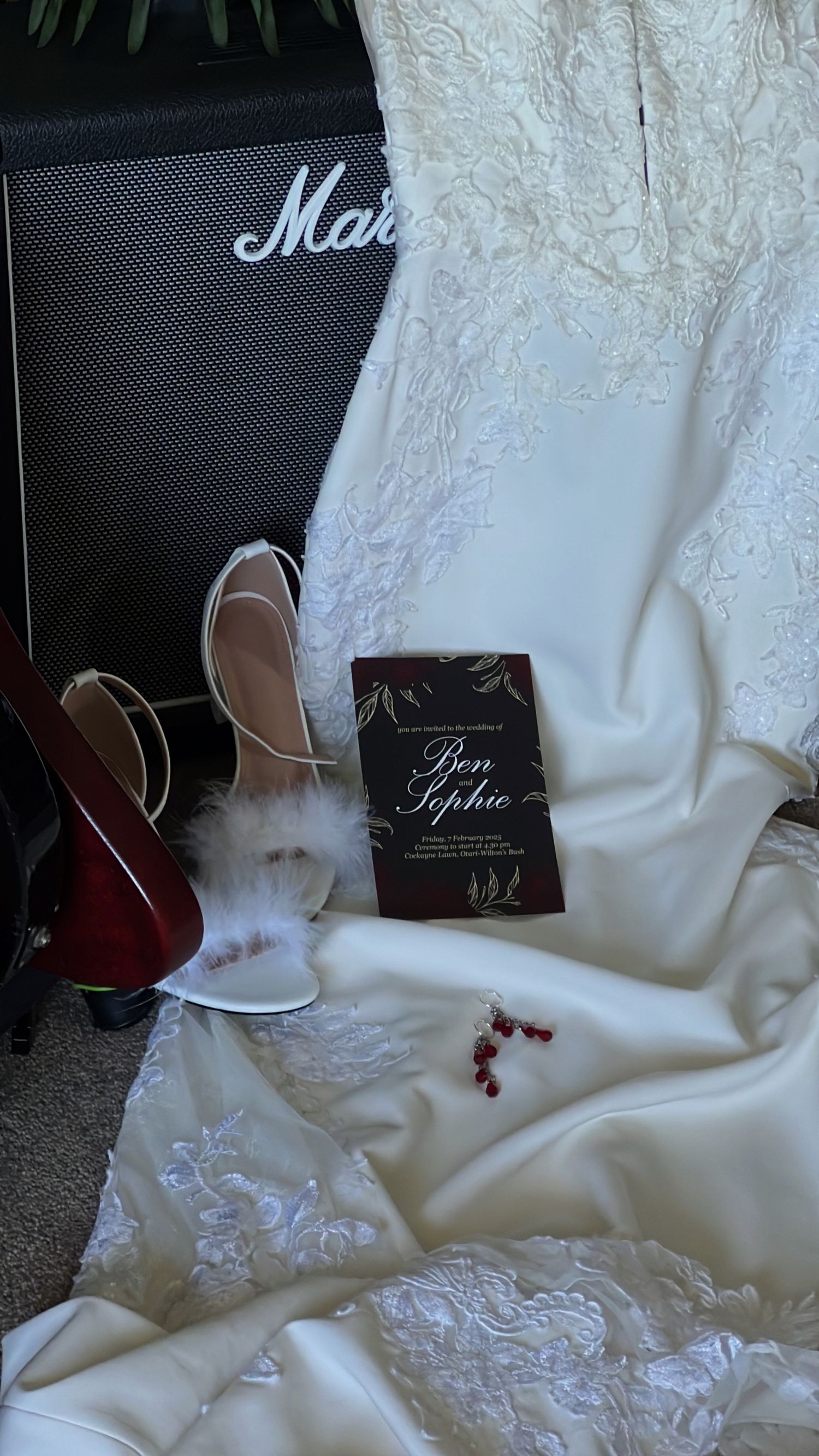Elegant white lace wedding dress laid out with accessories and packaging.