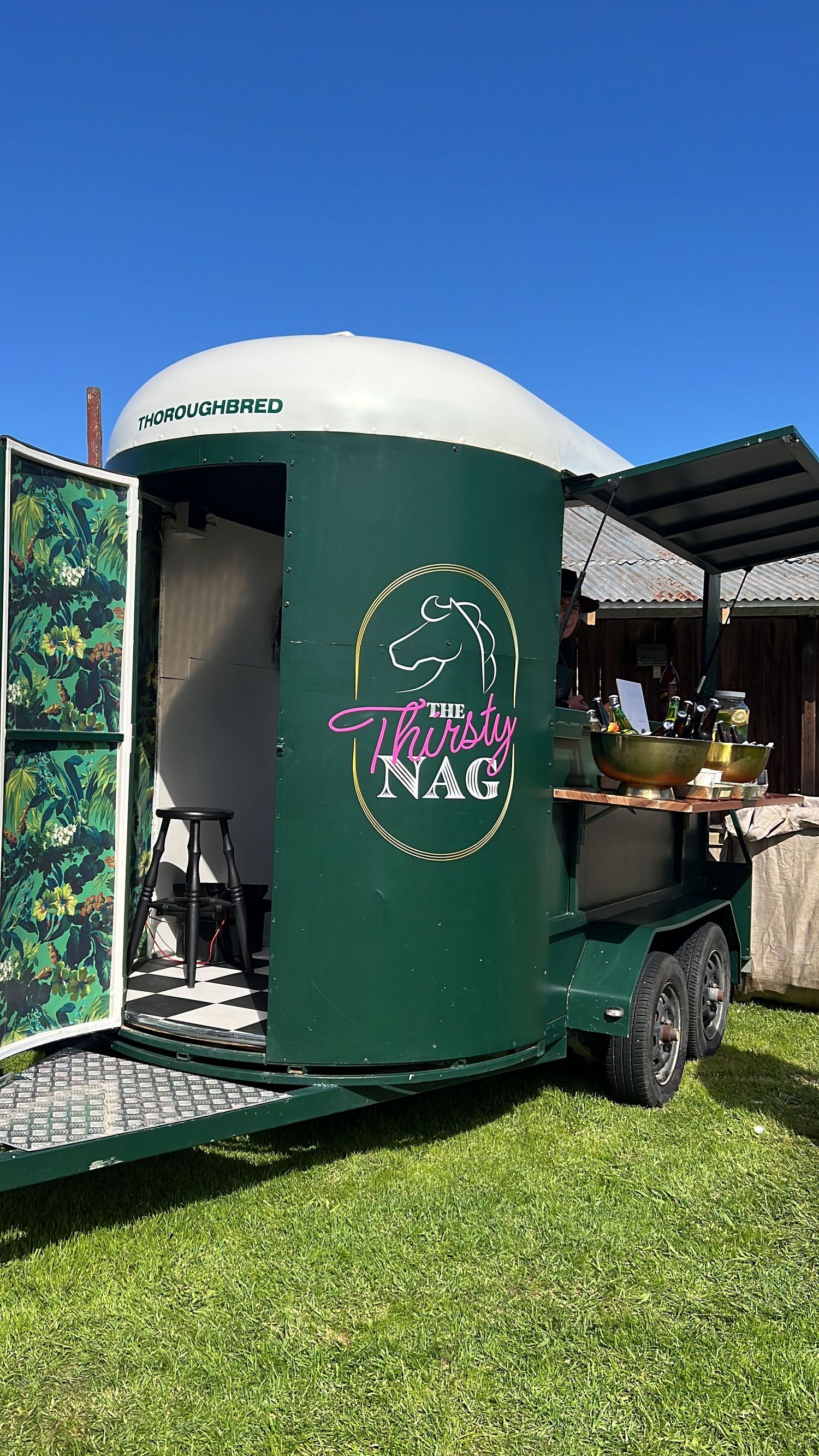 Green mobile catering trailer with 'NAG' branding parked on grass at an outdoor event. content creation in new zealand