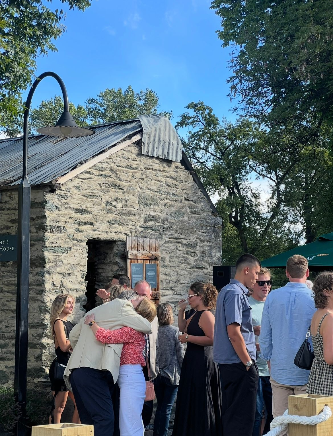 A group of tourists gathers outside a historic stone building during a guided tour.