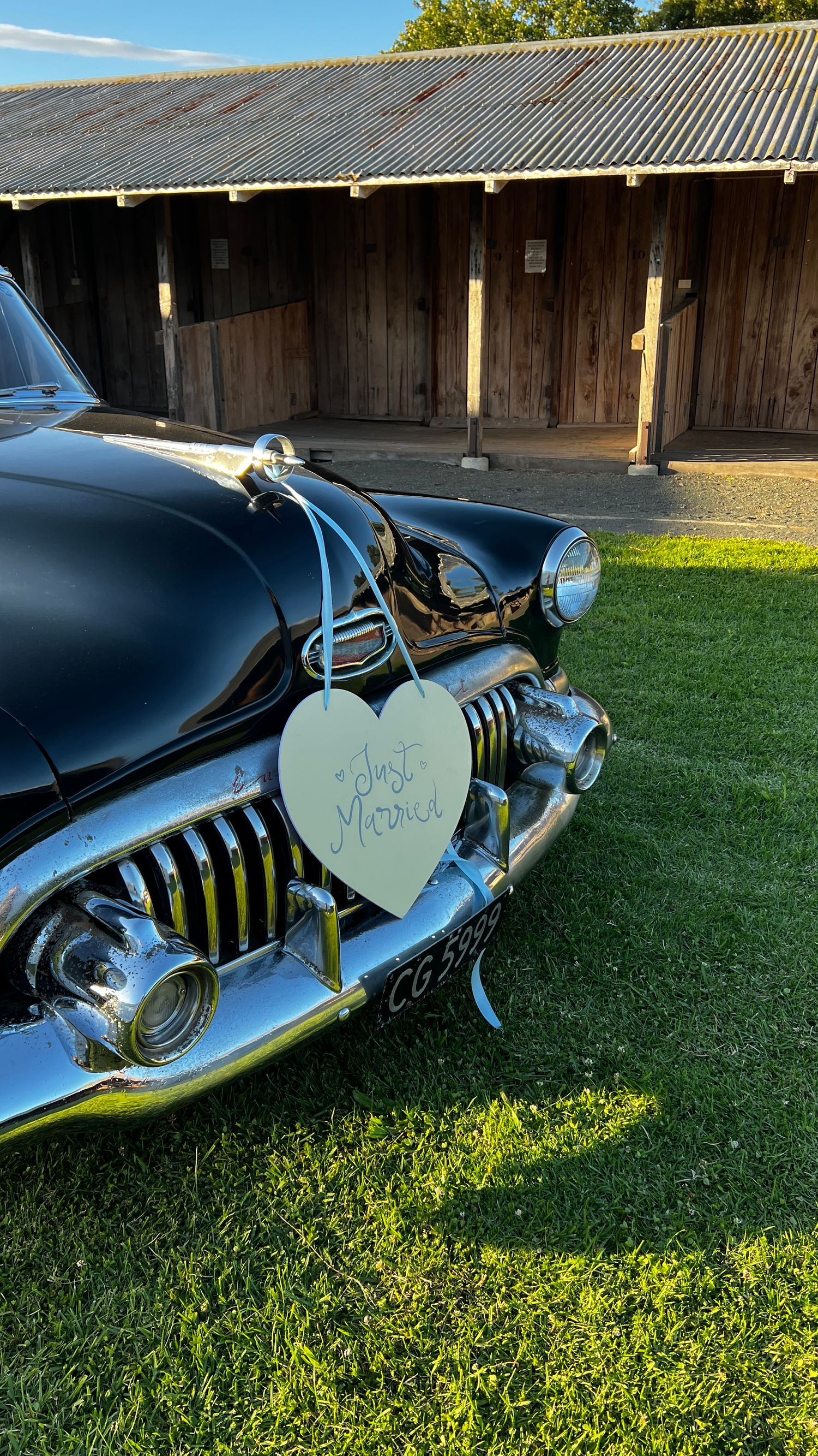 Classic black vintage car decorated with heart-shaped wedding signage.content creation in new zealand