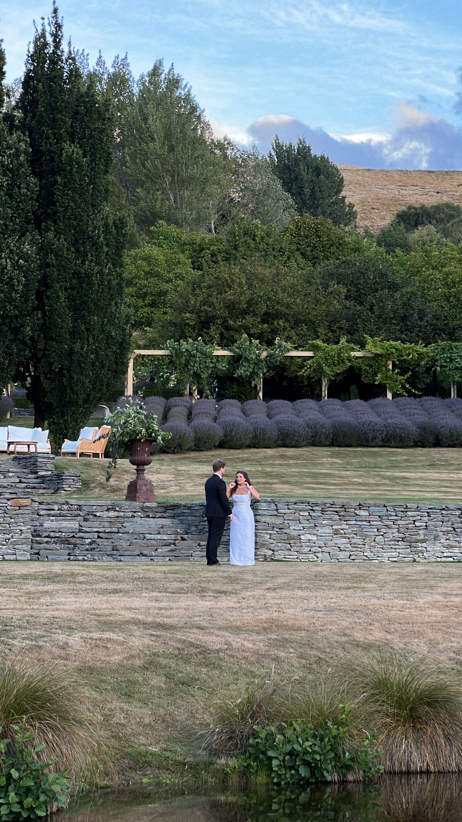 Outdoor wedding ceremony site with stone wall and mountain views in background.